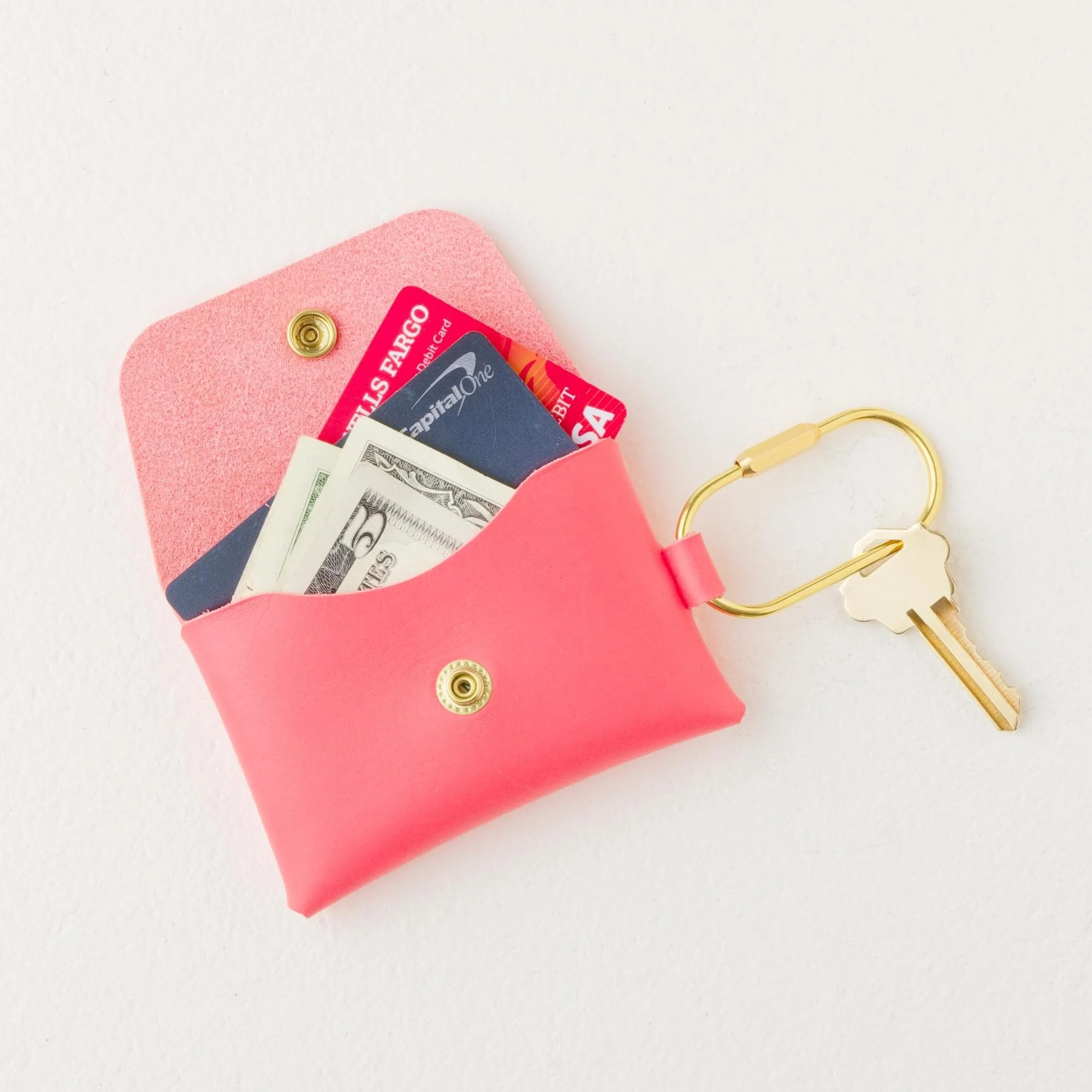 Personalized leather coral color carabiner keychain wallet with gold finish hardware, open with cash, credit cards and key attached to carabiner.