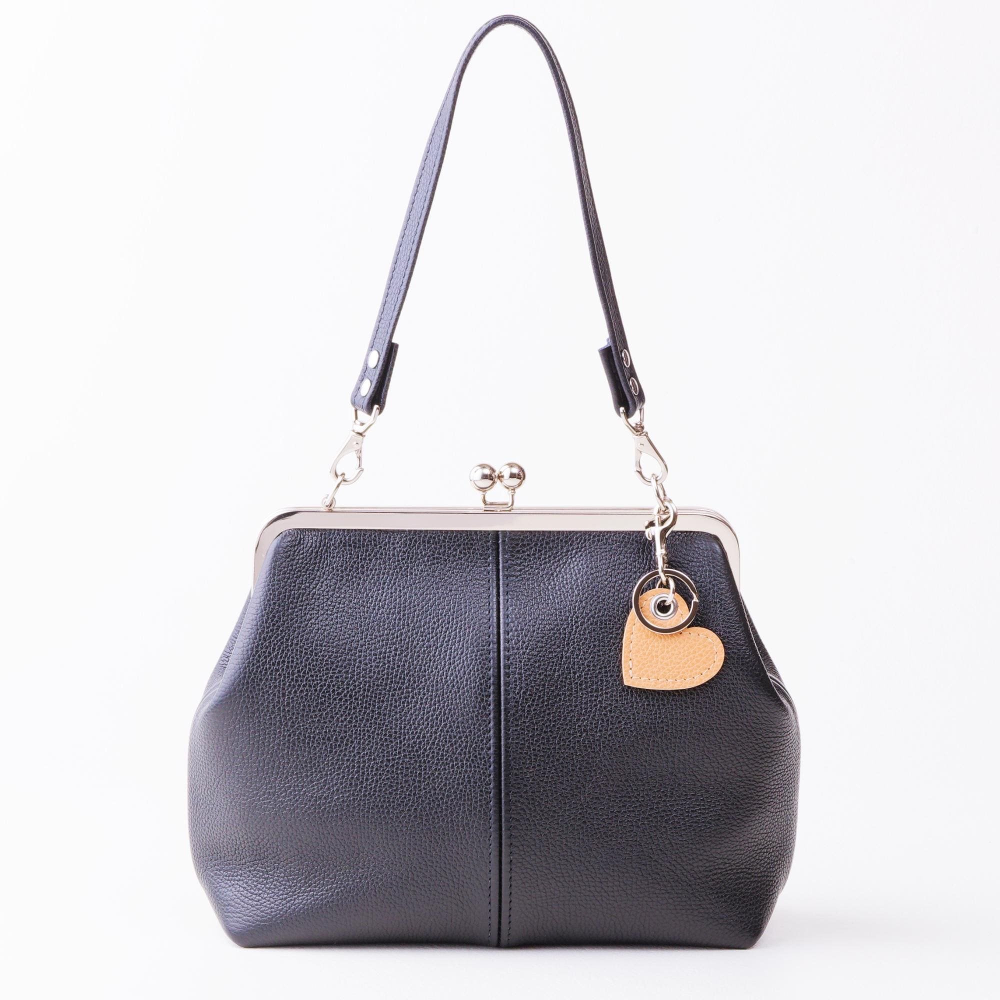Tan leather keychain purse charm attached to black leather kiss lock handbag with silver finish hardware.