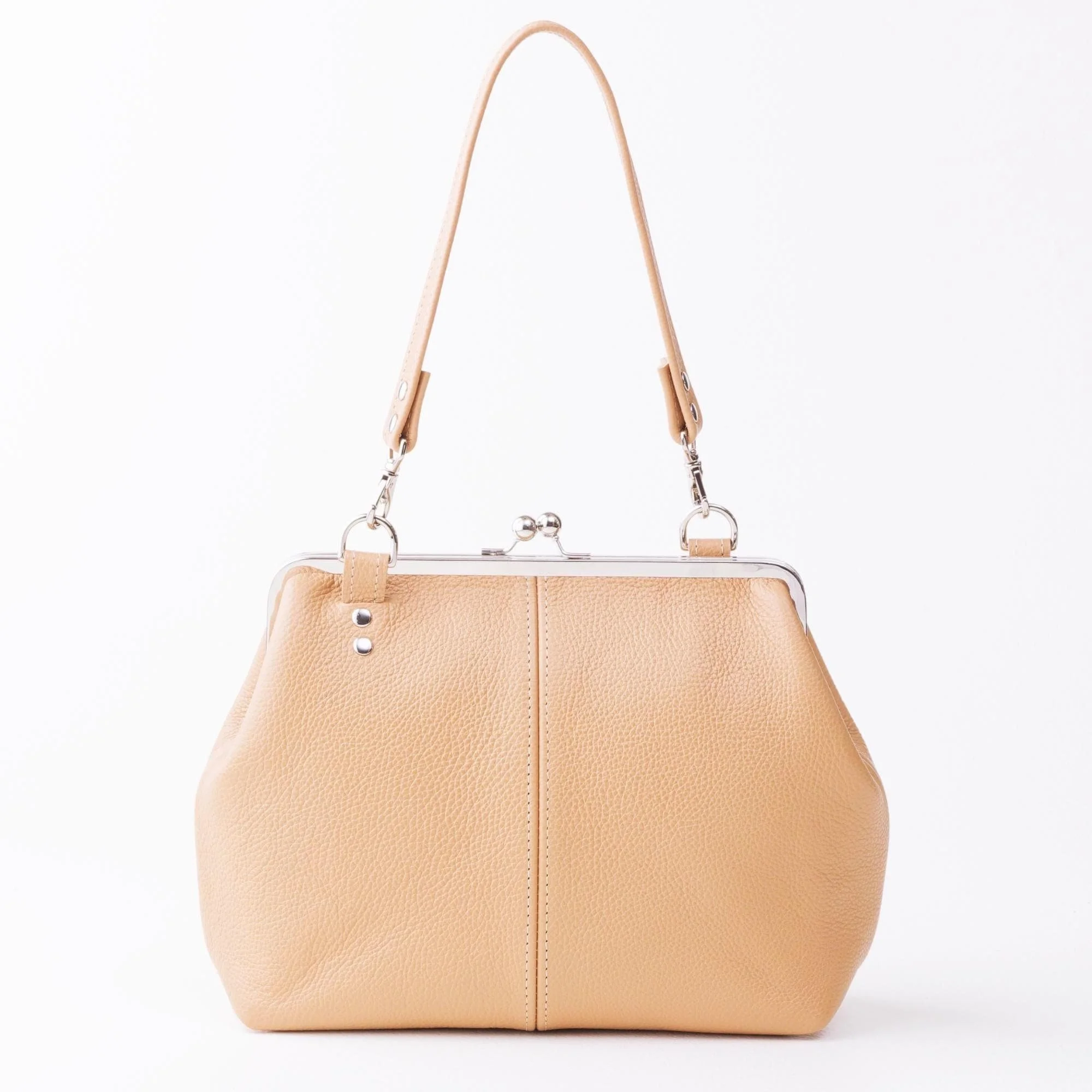 Front view of tan pebble grain leather kiss lock handbag with silver finish hardware and shorty shoulder strap on tabletop.