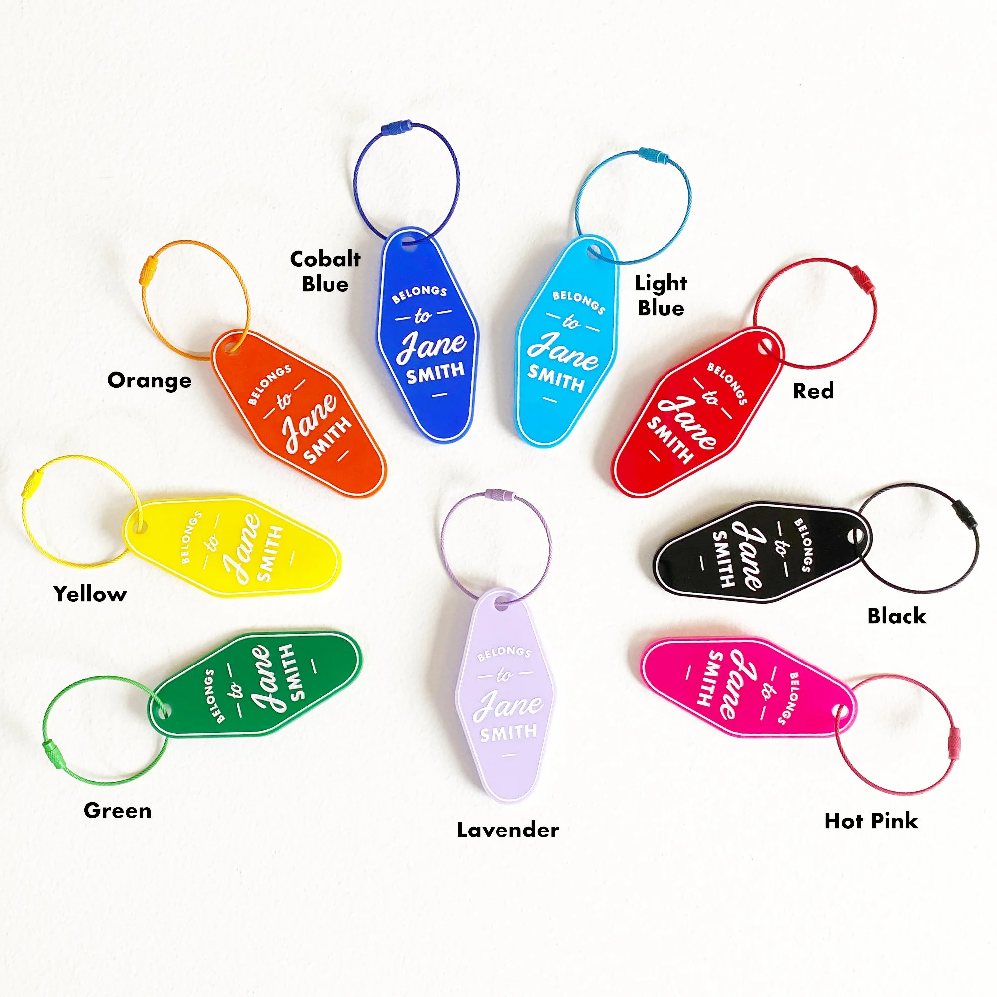 Fanned out top view of nine different colored personalized laser engraved acrylic luggage tags with color descriptions.