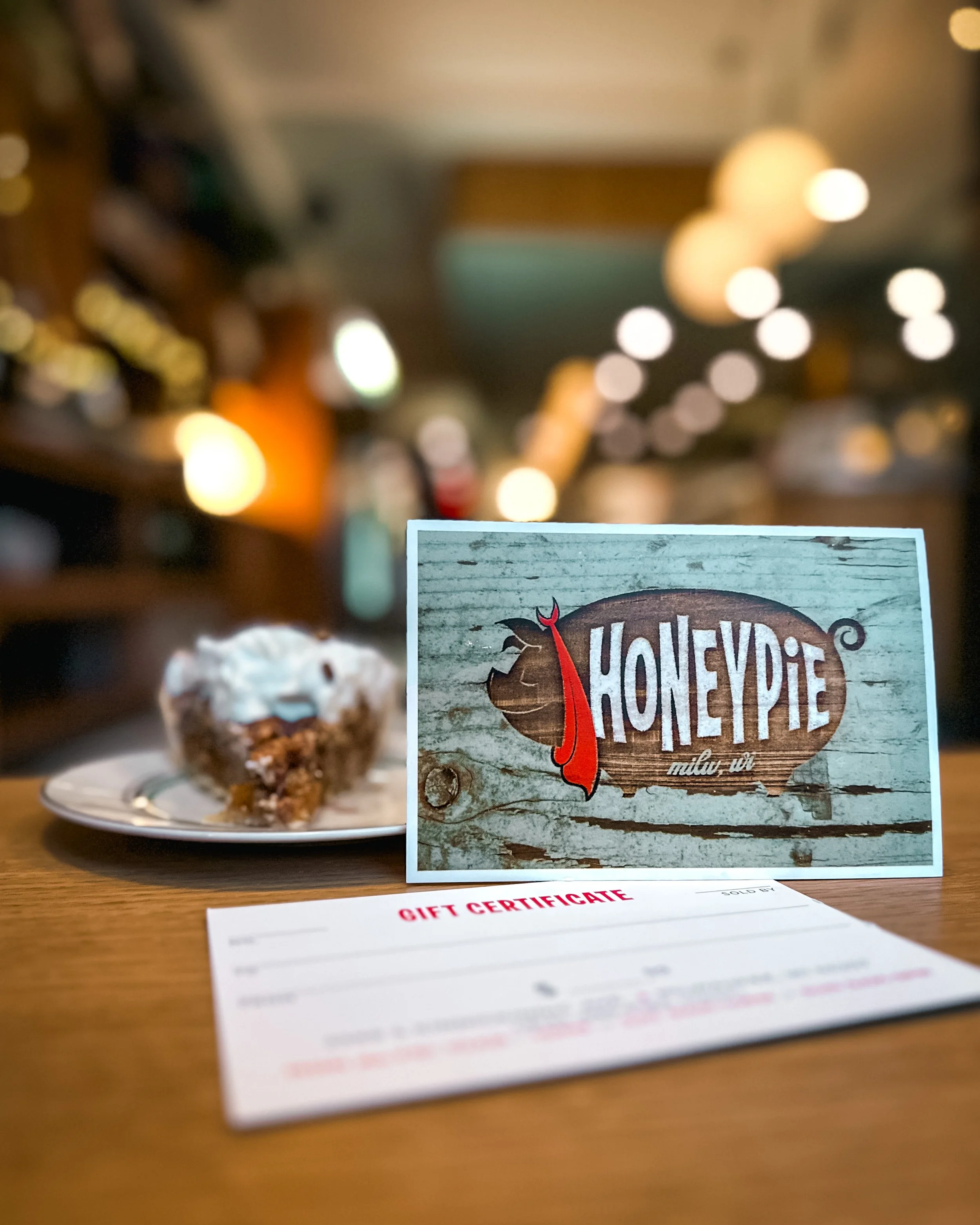 Honeypie gift card on a table with a slice of pie in the Honeypie lobby.