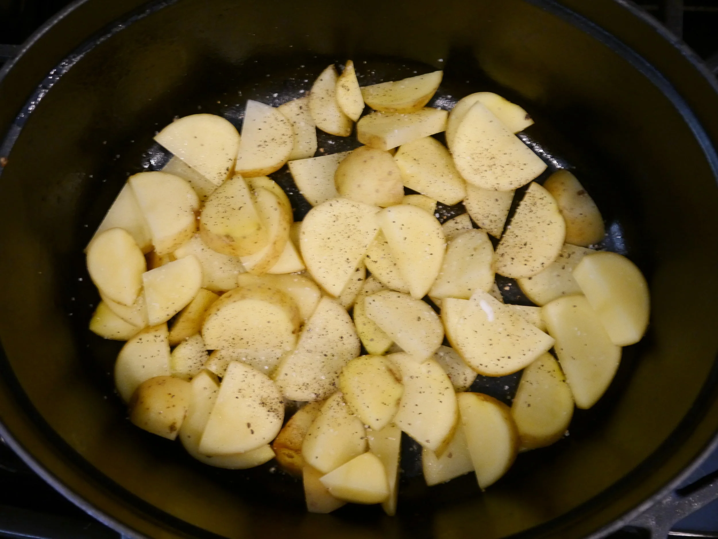 After the stock has cooked down, layer the potatoes in the pot. 