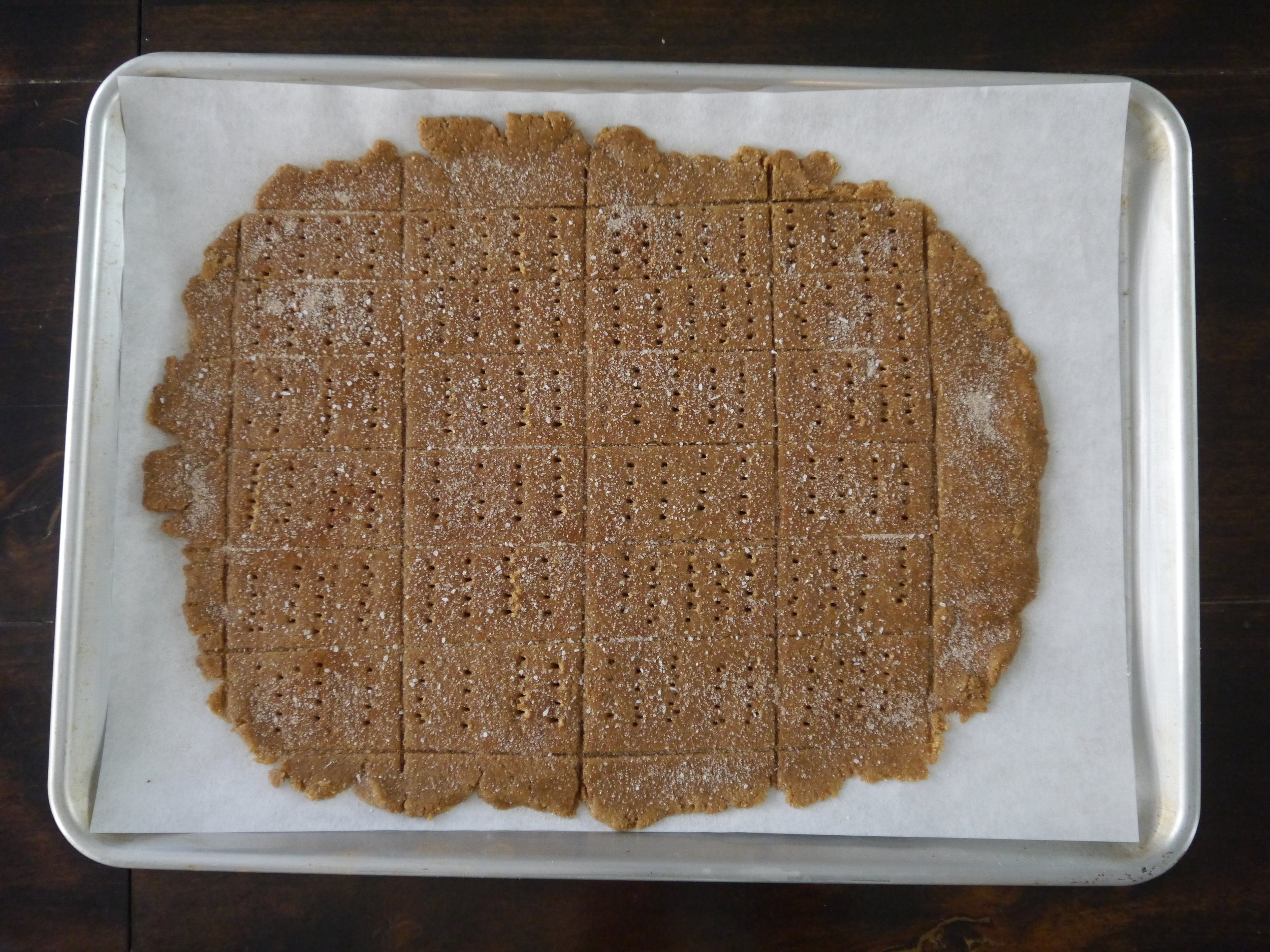 Using a bench scraper or knife, cut the rectangle into 1-by-2-inch rectangles, then poke the crackers with a fork to make dots. Slide the parchment (with the dough on it) onto the cookie sheet.
