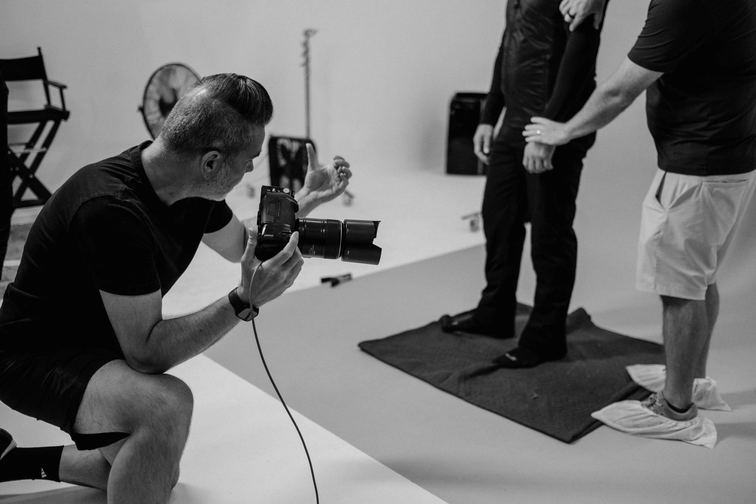 Photographer taking a photo of a group of people during a fitness or yoga class, with a focus on a person on a mat.