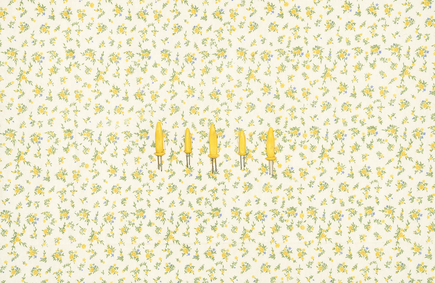 Corn Cob Holders on Tablecloth with Yellow Flowers