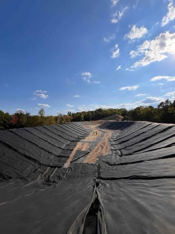 Seamed geomembrane panels running down the side slopes of a large lined basin