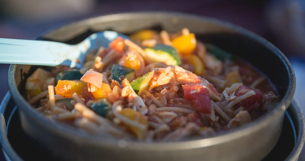Pot full of chicken veggie tomato pasta.