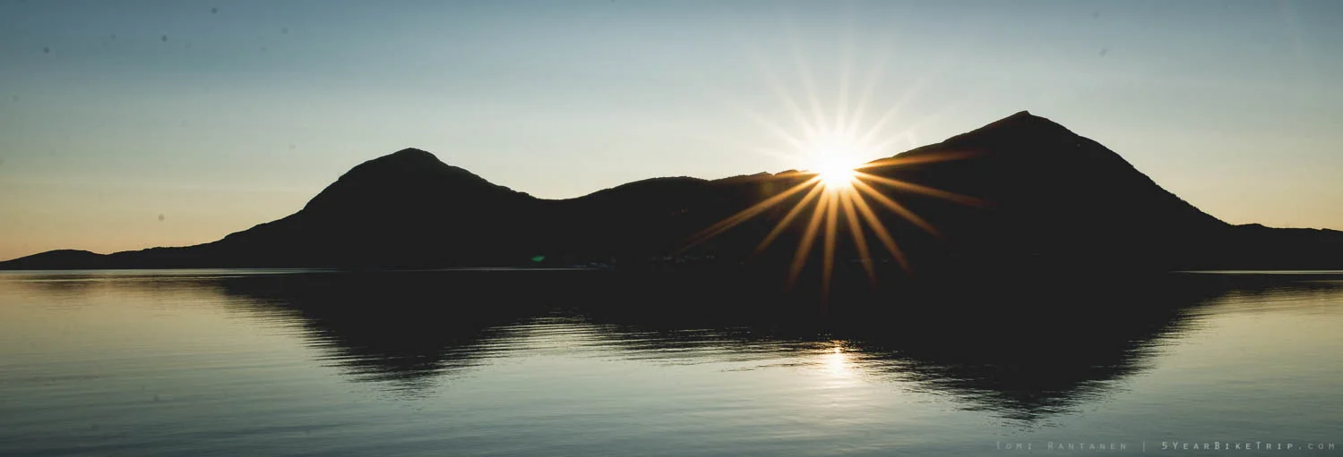 Sun setting behind a mountain on an island.