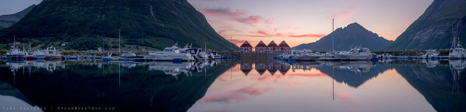 Still harbour and mountains reflected off the water.