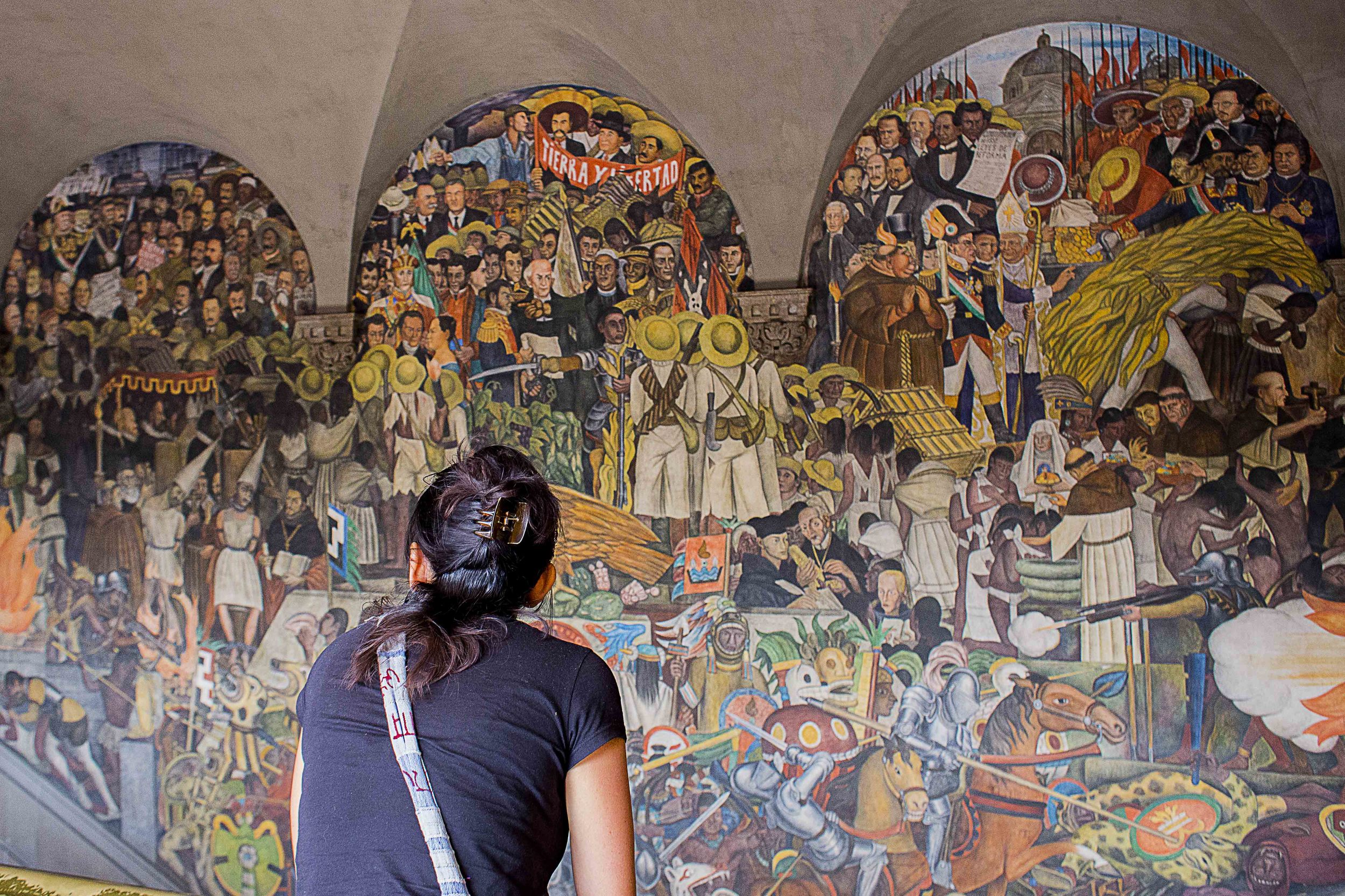 Day 88 - Mexico City, Mexico Inside the National Palace is a mural depicting the Mexican history by Diego Rivera. Much like Orozco, his style focuses on the struggle the Mexican people, mainly indigenous and mestizo, that have endured during the times of Conquest and Revolution. It was his opportunity to provide an alternative view of history in favor of the Pueblo and a chance to vilify the Spanish as a means of rectifying a historical imbalance. The palace itself was built on the ruins and materials of the original Aztec palace.