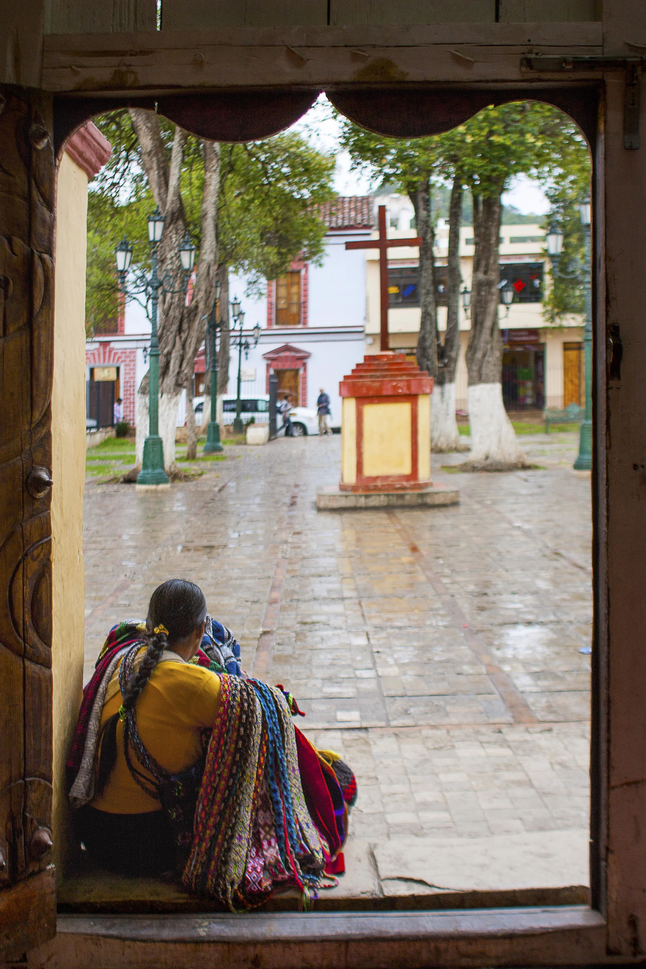 Day 127 - San Cristobal de las Casas, Chiapas, Mexico We take a day off from tours and walk around the cobbled streets of San Cristobal to take it all in. It happened to rain so the usual hustle of the streets was missing. Here, a lady waits for the rain to stop at the steps of a church so she can go back to selling her crafts.