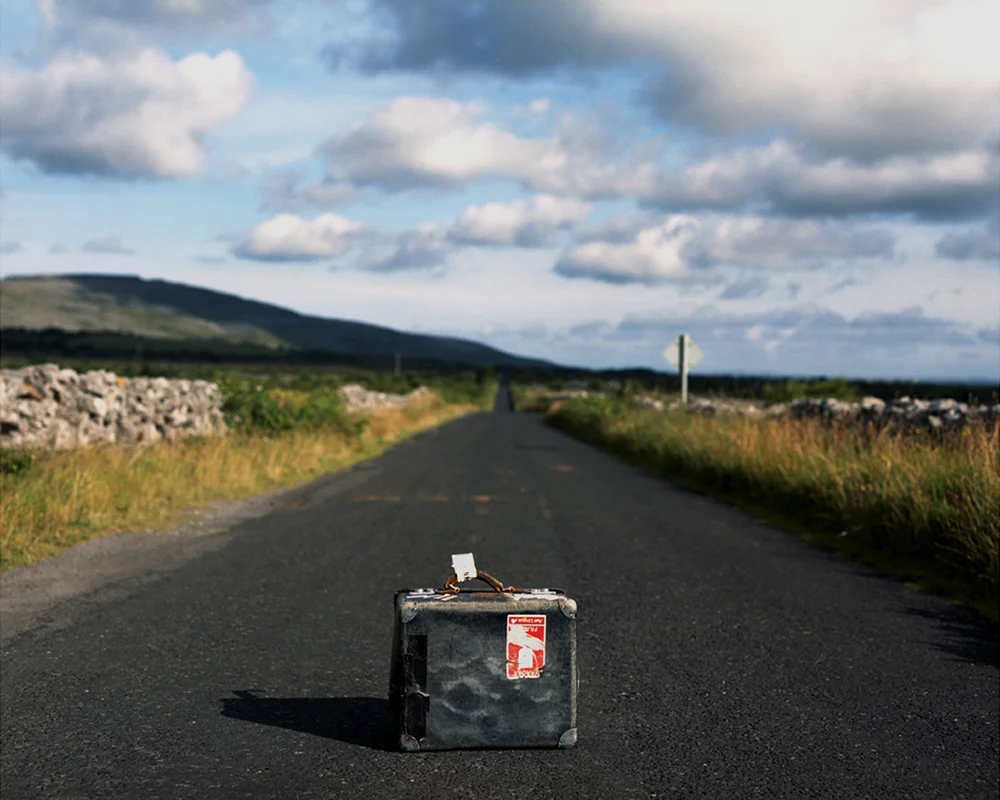 The suitcase as an object was found by chance in a second hand store in North London. It already had well-worn travel labels for journeys between London, Paris, and Ireland, which could easily have been my own. It was the perfect image of the memory of journeys made, and the memory of emigration. It became a device to visually represent wandering, or a sense of displacement, relevant beyond the personal and relating to historical as well as contemporary experiences. Thoughts rather than destinations were printed on travel labels to accompany images in this series. 