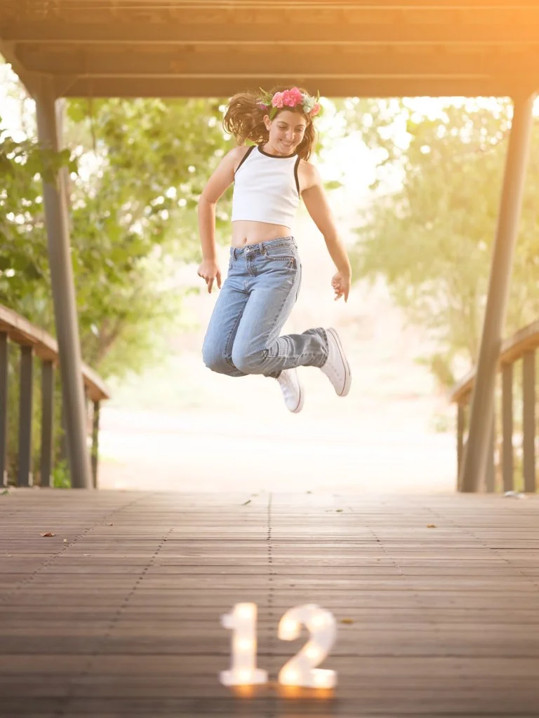 Bat mitzvah photography of girl jumping on wooden bridge