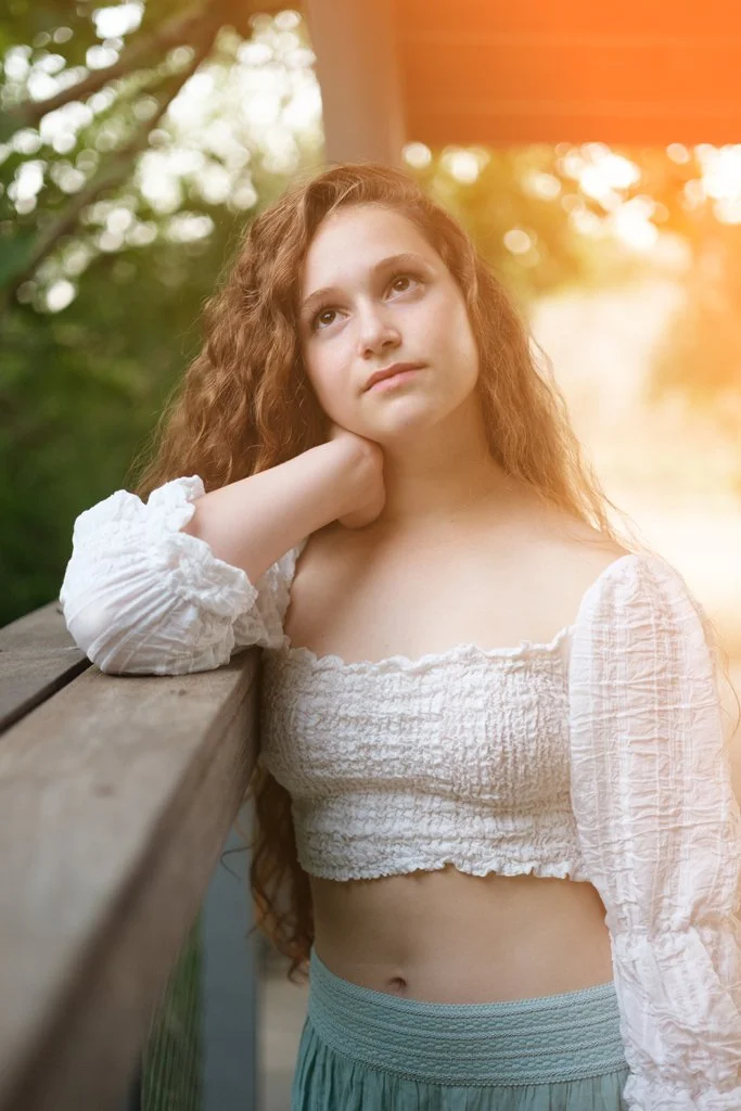 Bat mitzvah portrait of girl leaning on wooden railing outdoors