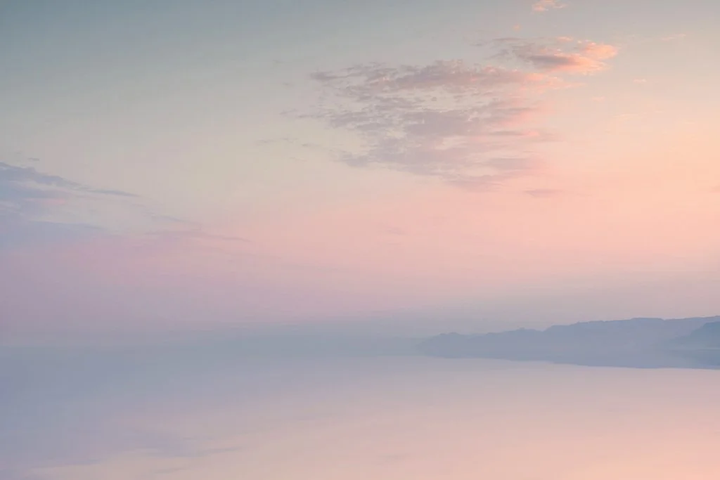 Soft pastel sky over a calm horizon with minimal clouds at sunset.jpg