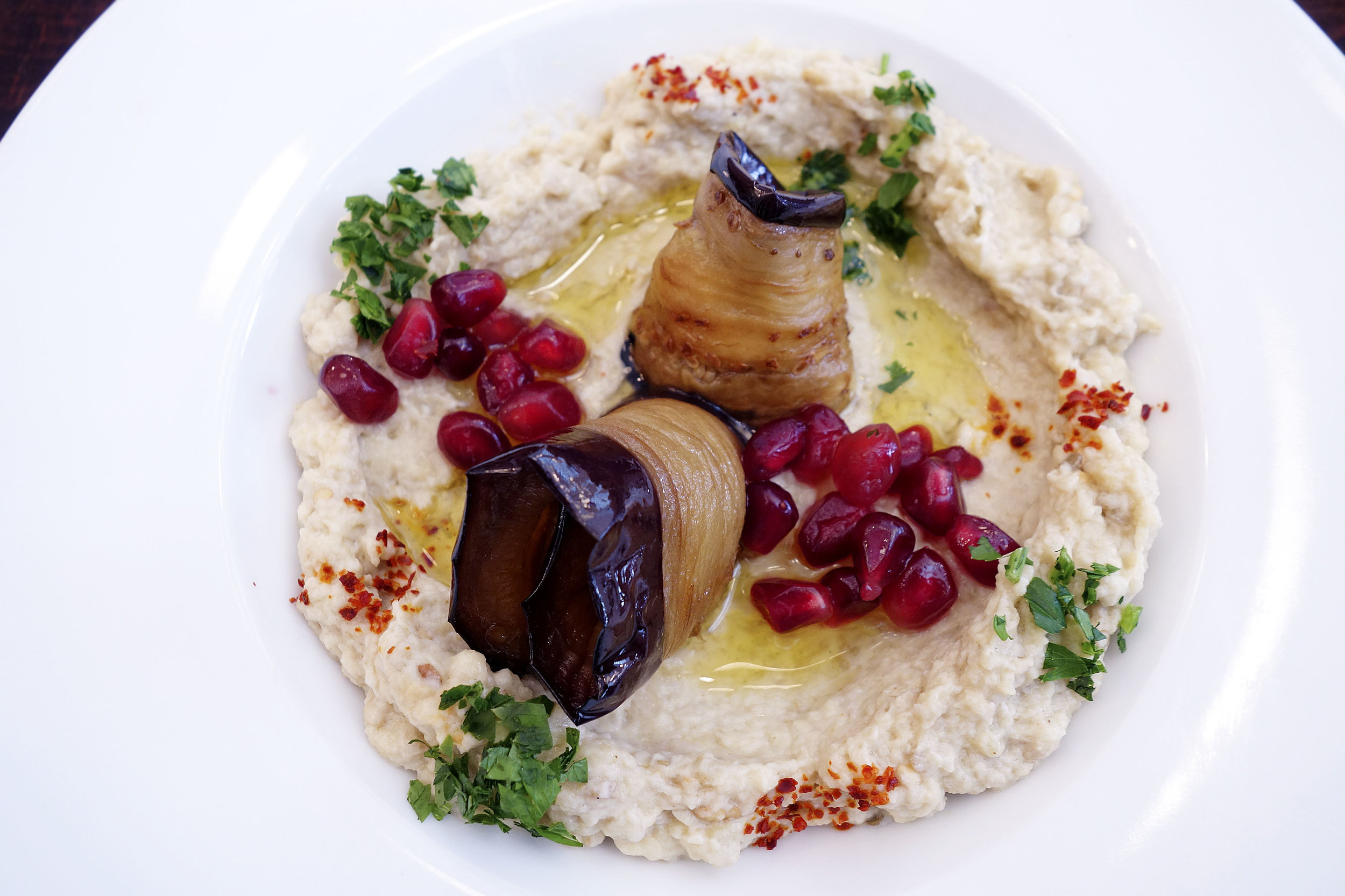 Hummus with pomegranate seeds and roasted eggplants.