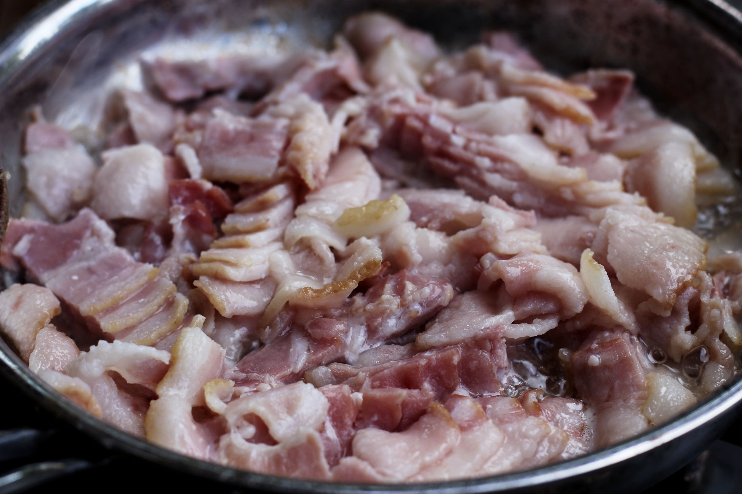 Bacon is dropped into a cold pan and warmed up on medium heat.