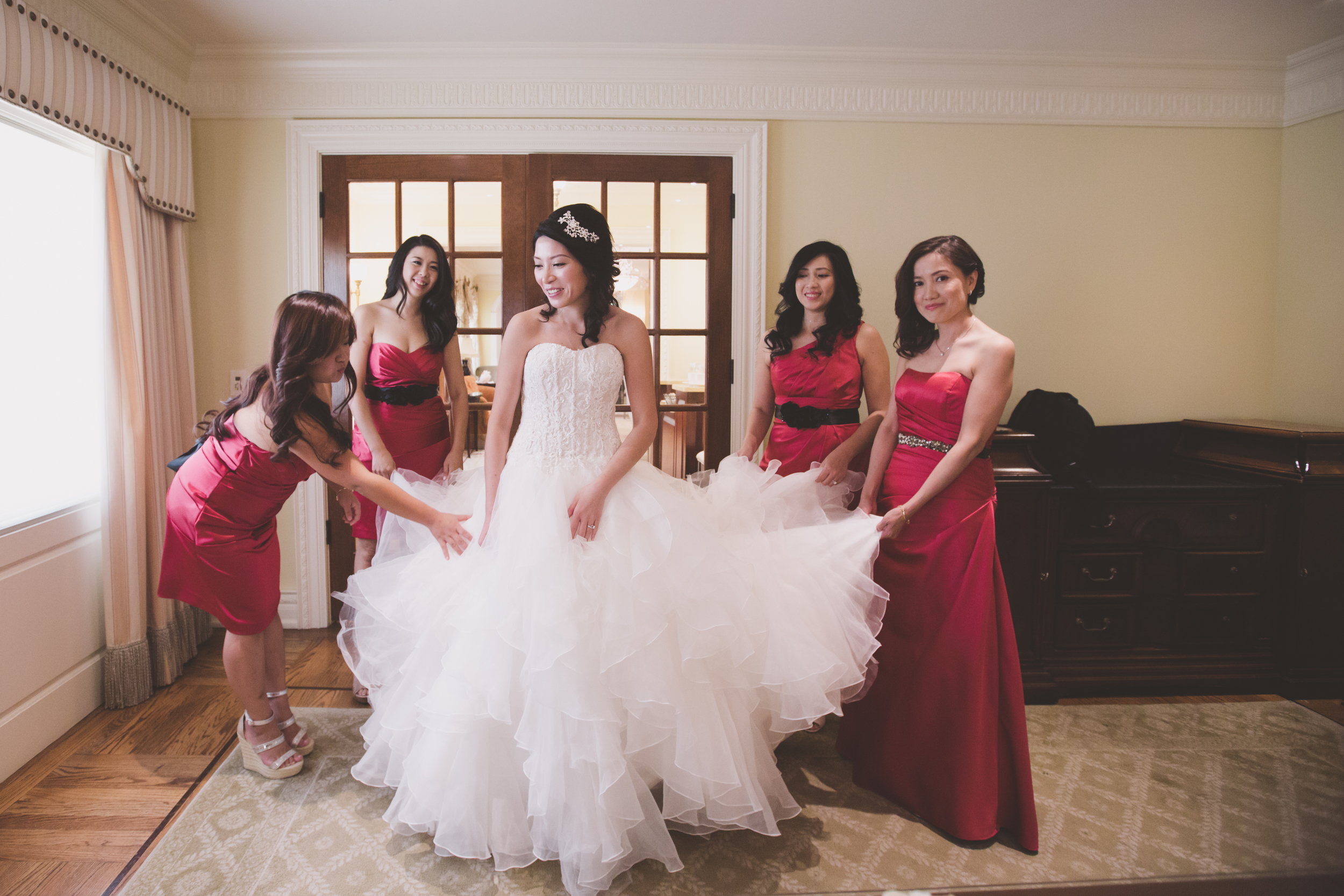 bride and bridesmaid getting the dress on 