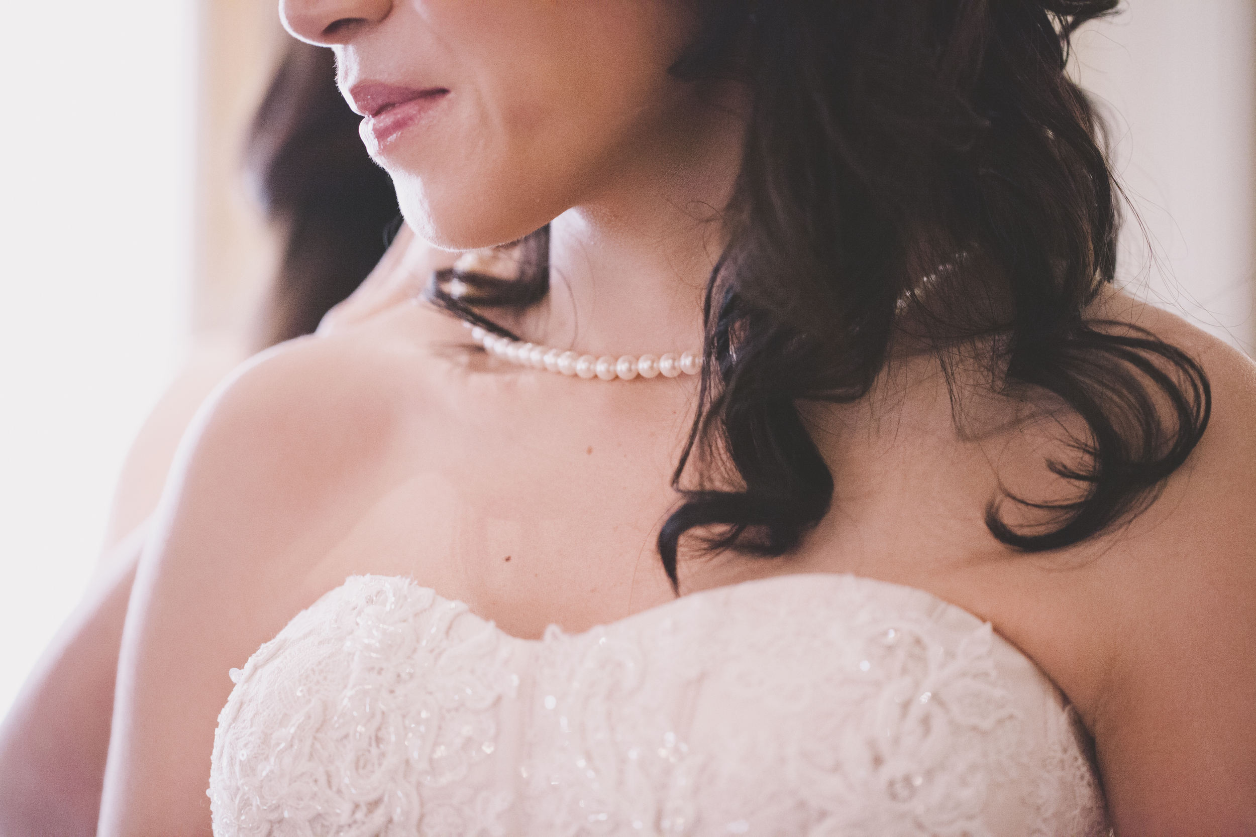 close up pearl necklace in wedding dress bride