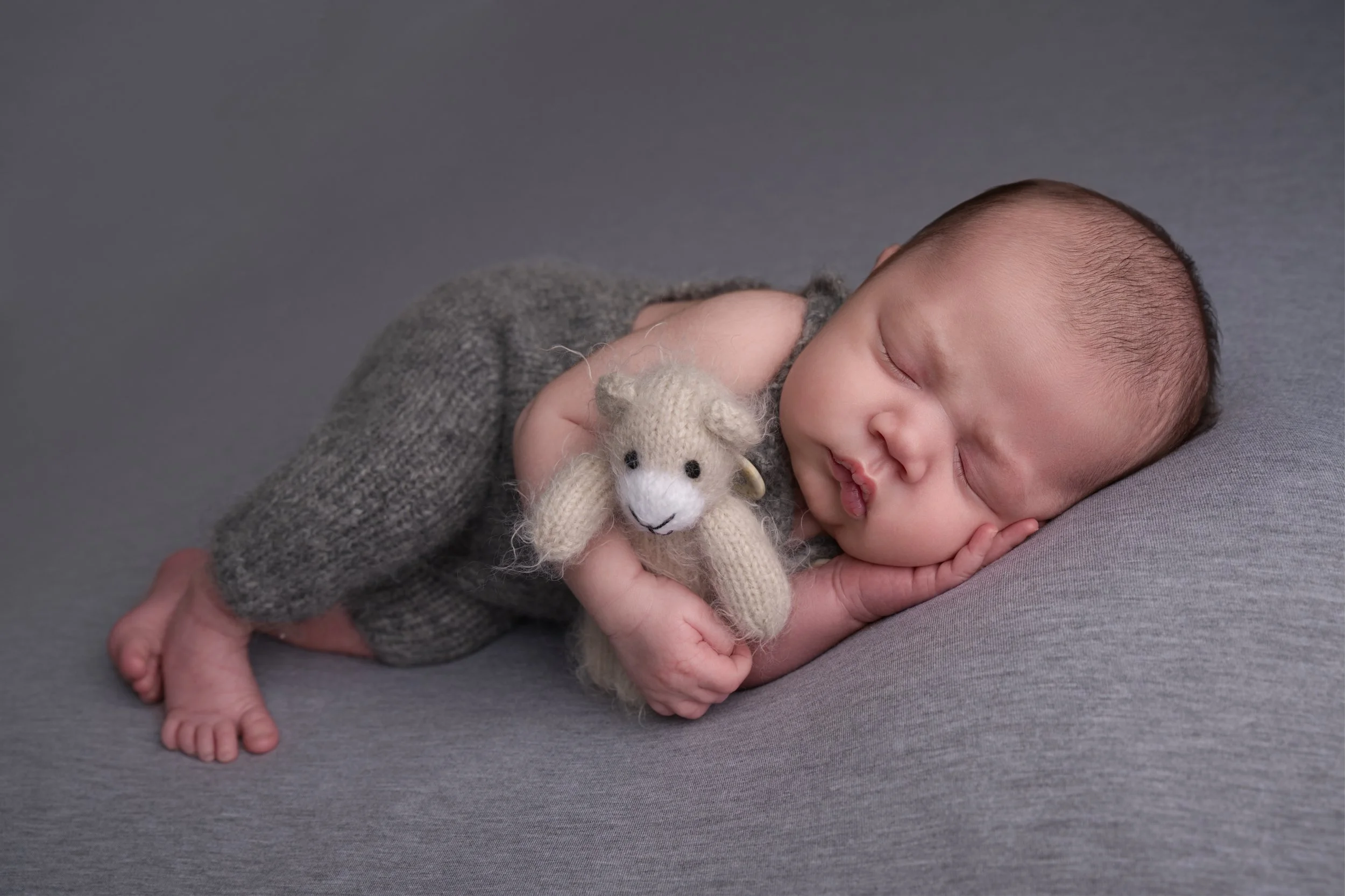 Baby boy on grey blanket with teddy