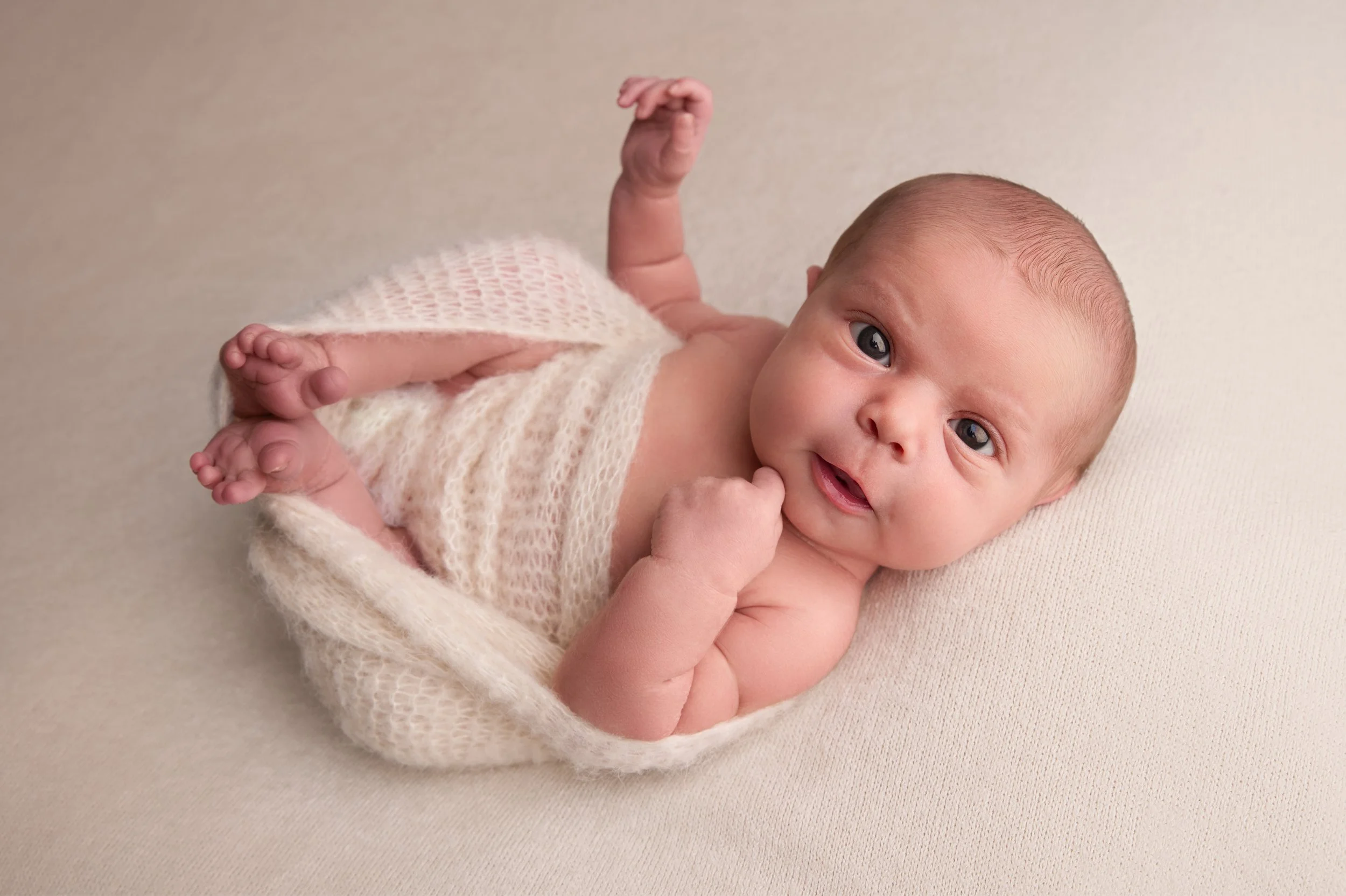 Awake baby on cream blanket