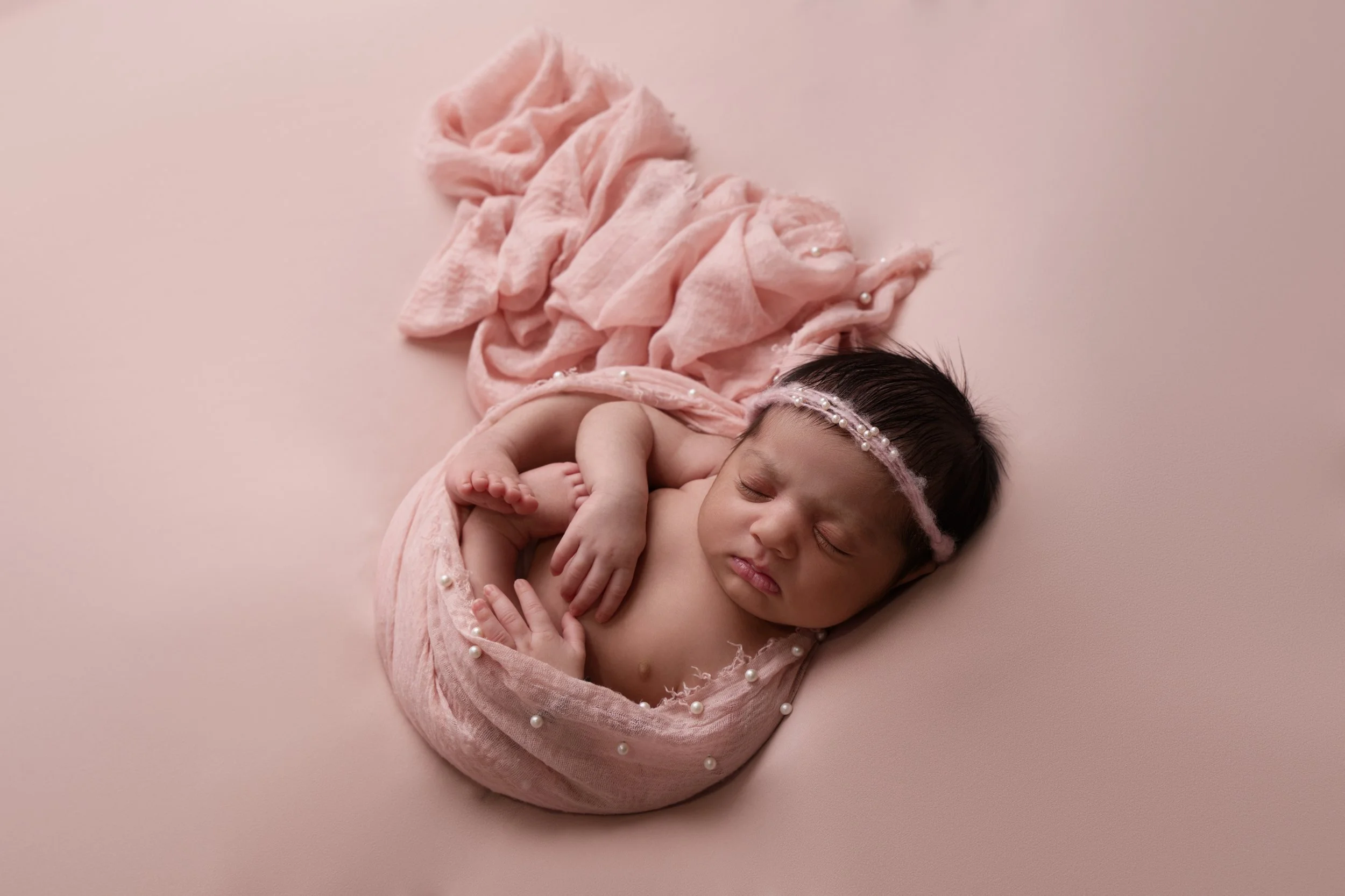 Baby girl swaddled on pink blanket