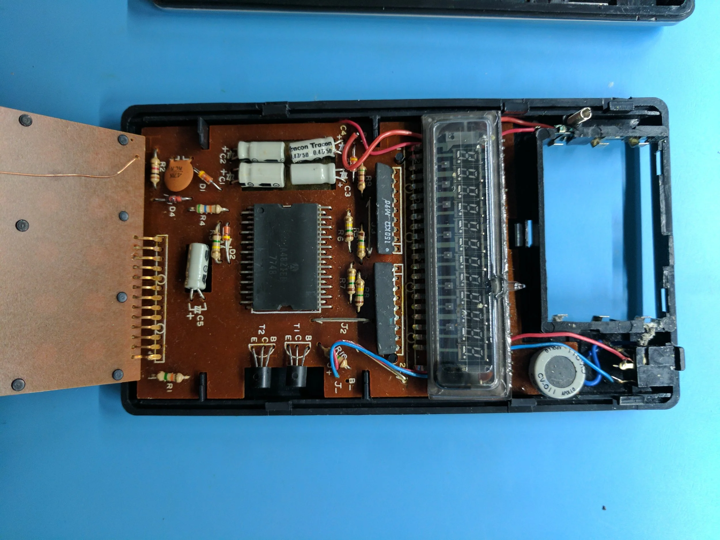The insides. In the center is the A4821, date code 48th week of 1977. The VFD is toward the right, and the round-looking thing next to it is actually a DC-to-DC converter to provide -14.5v to the chip, and -31v to the VFD. The PCB on the left is the keyboard.