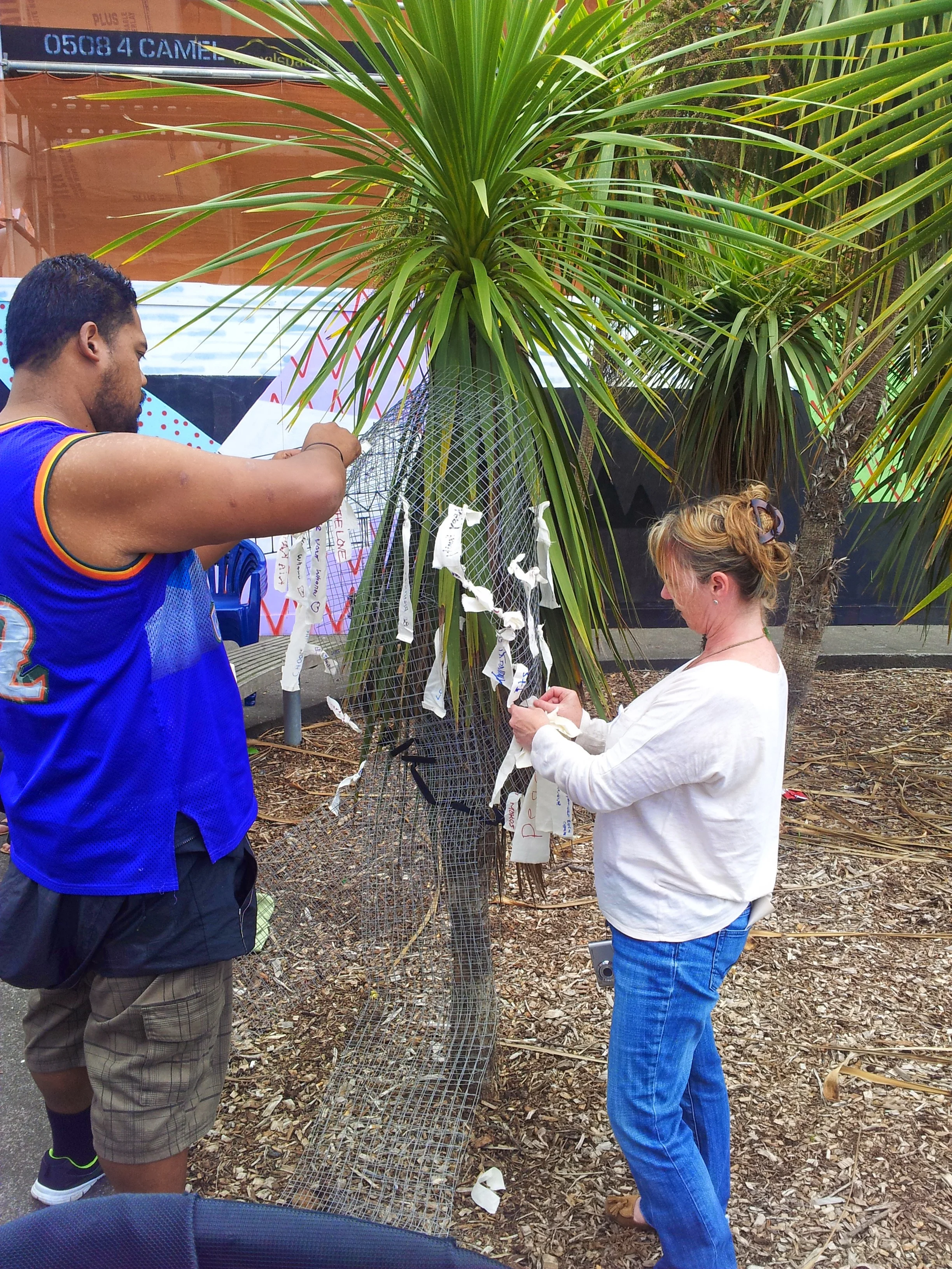 Locals in Glen Innes pin messages of hope to a wire ribbon for White Ribbon Day.