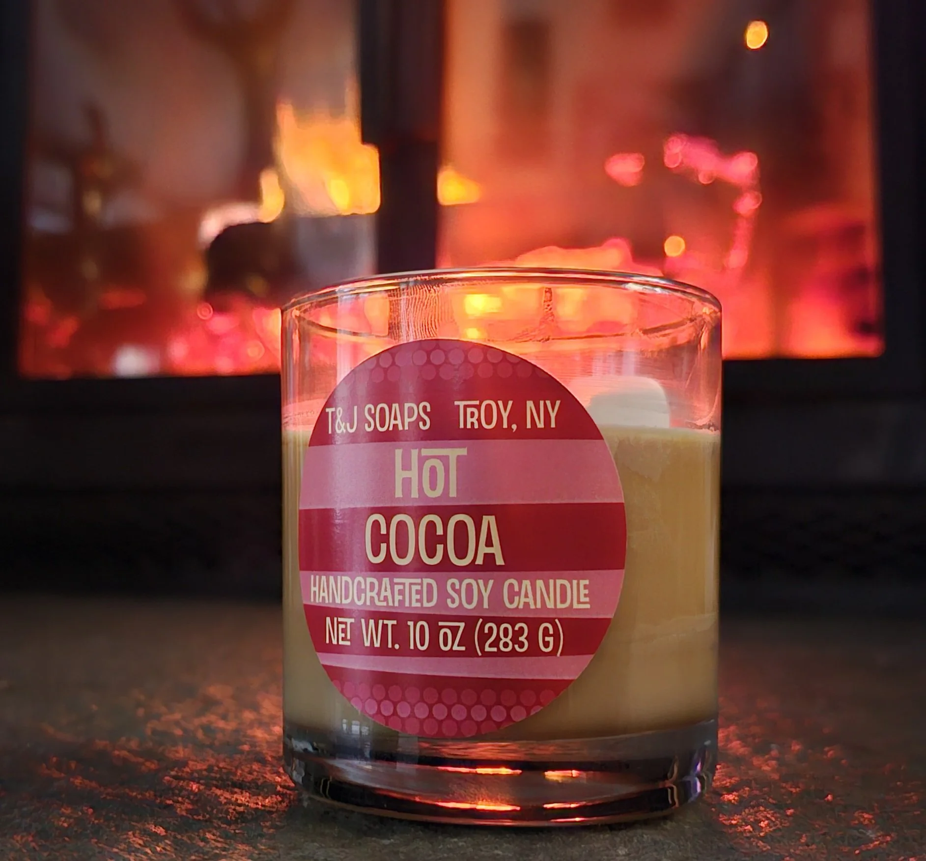 Hot Cocoa Soy candle sitting in front of a fireplace.