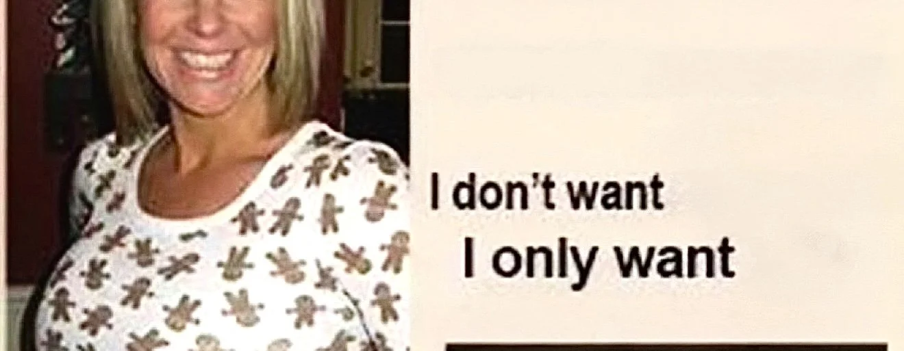 A woman smiling, wearing a white shirt with gingerbread man patterns, and standing next to a sign that reads "I don't want I only want."