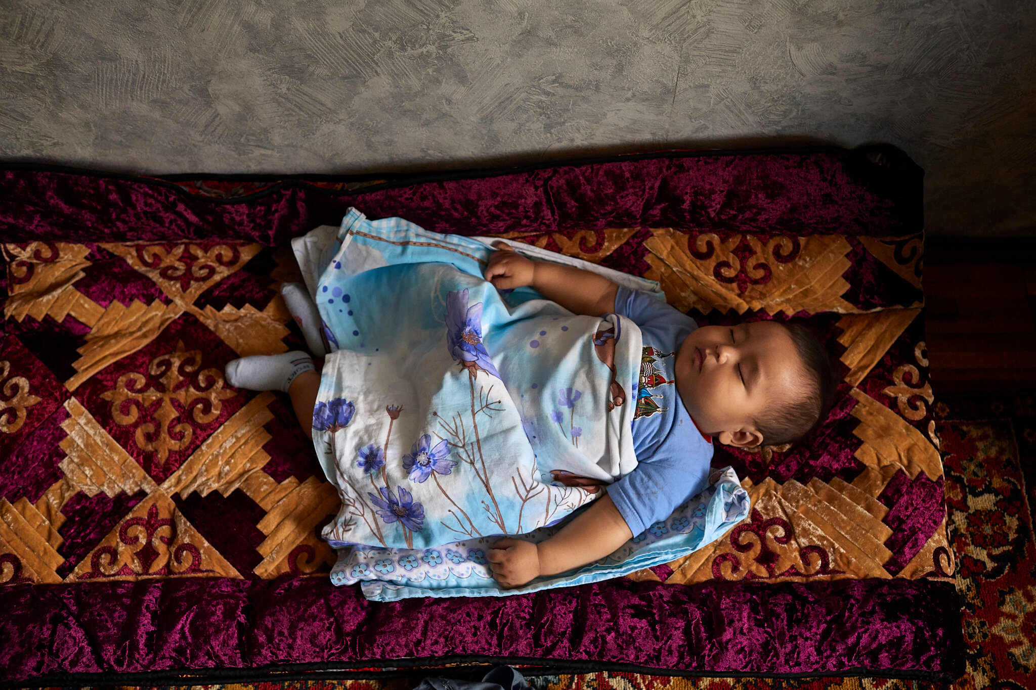 Russia, Moscow, 08/10/2019. 8-months old Kagan Adanov is sleeping on the national kyrgyz carpet “toshok”.