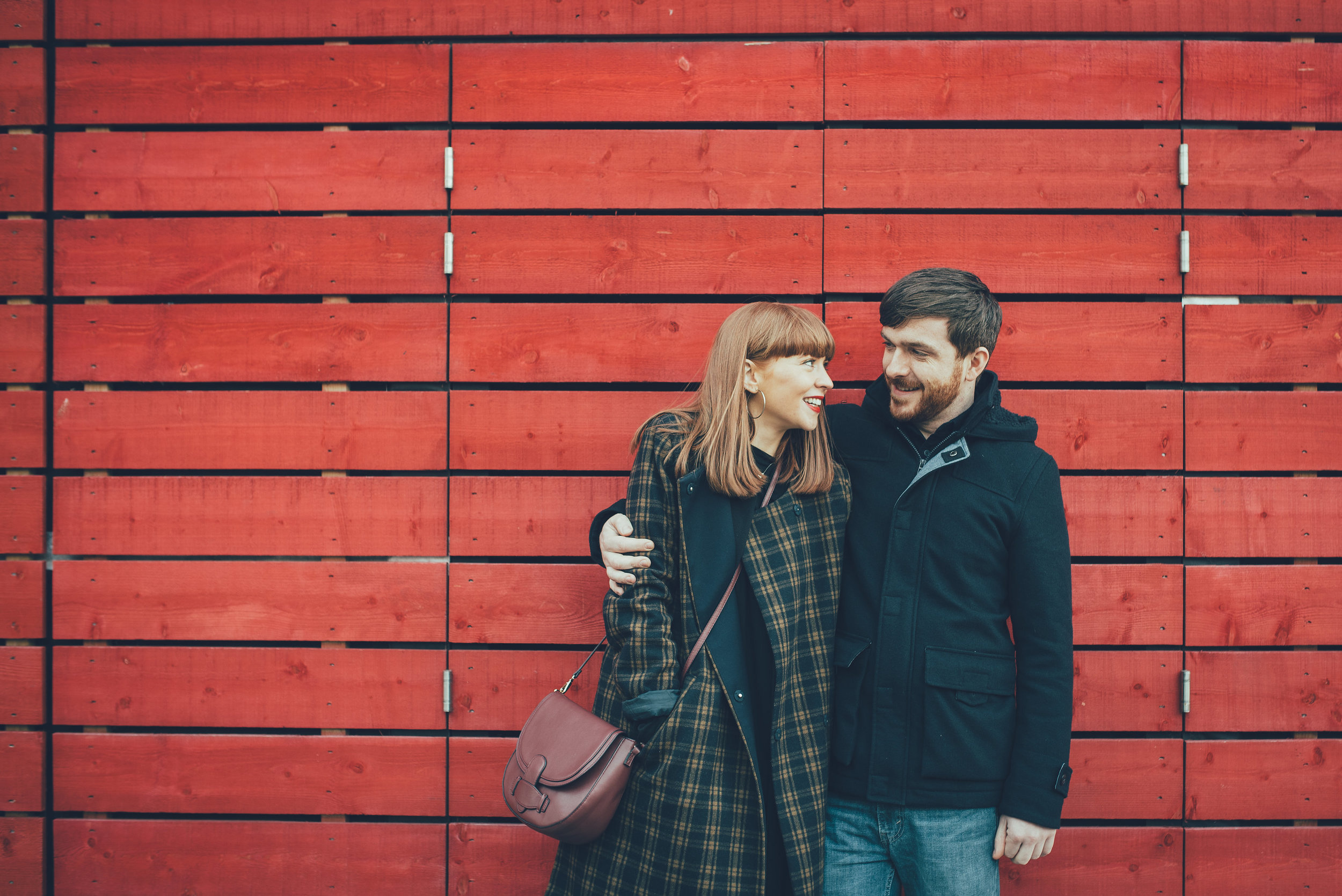 Couple in front of red wall at the National Theatre London