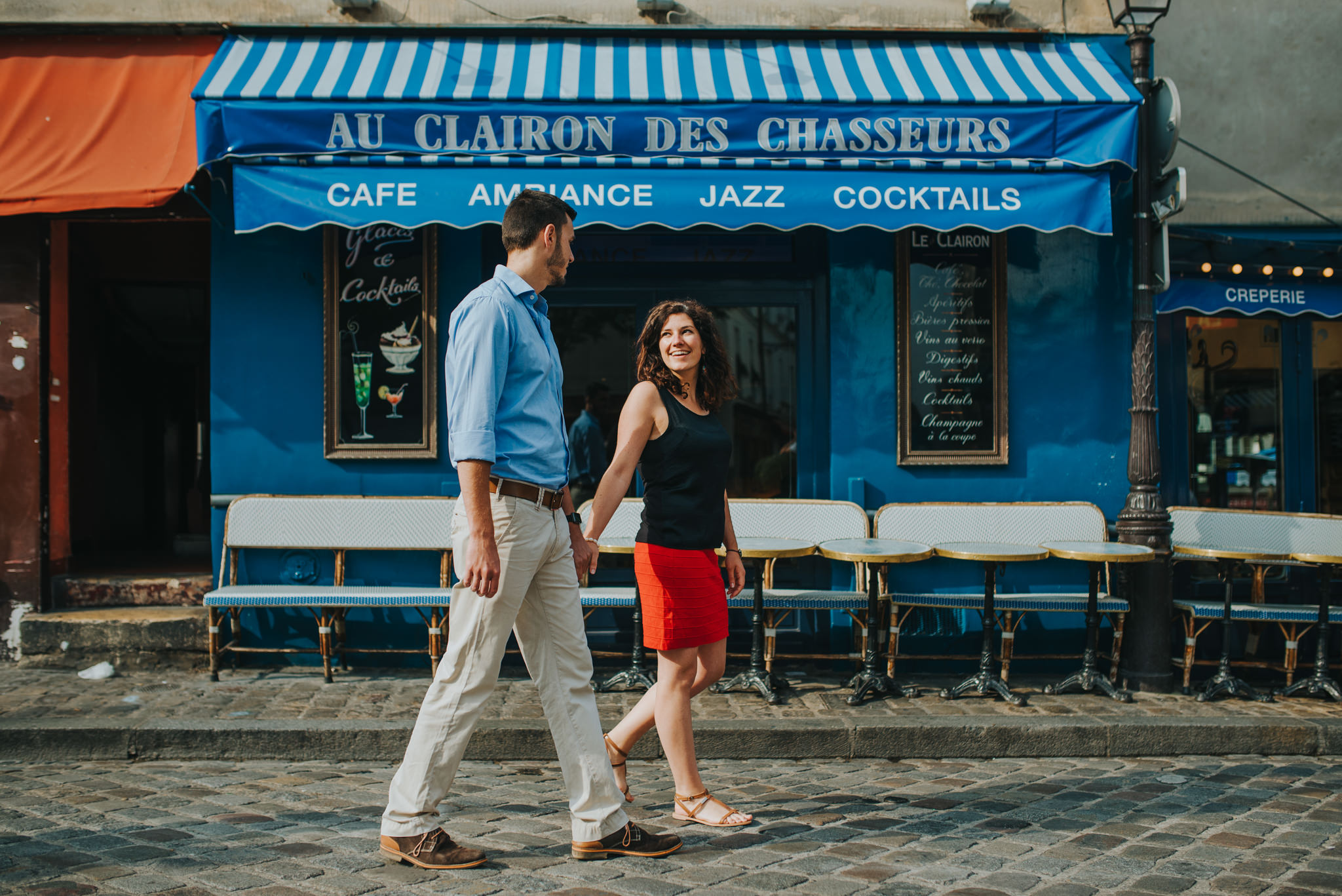 couple in love walking by a blue Paris cafe in Montmartre