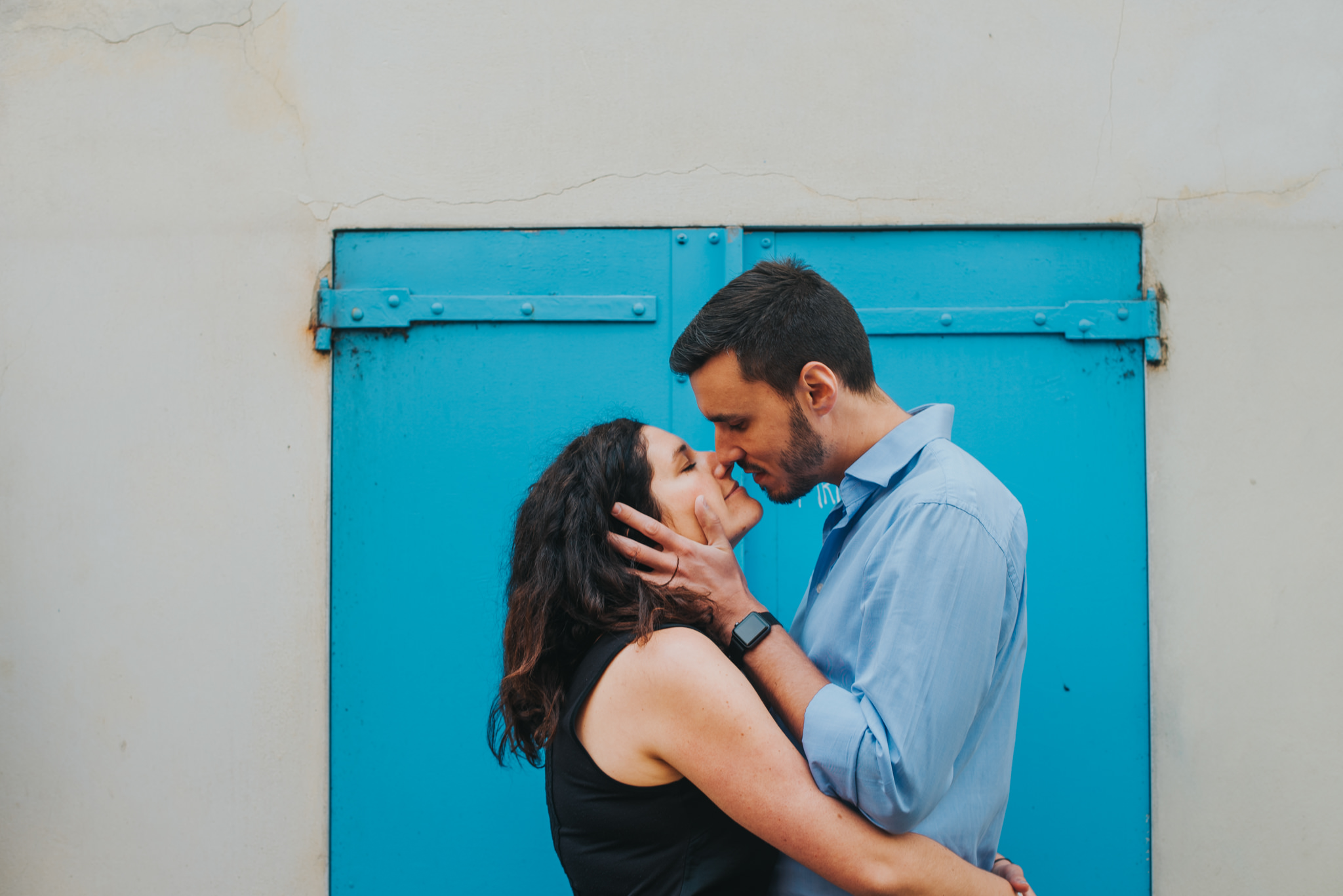 Couple in love kissing on Montmartre street with blue shutters in background
