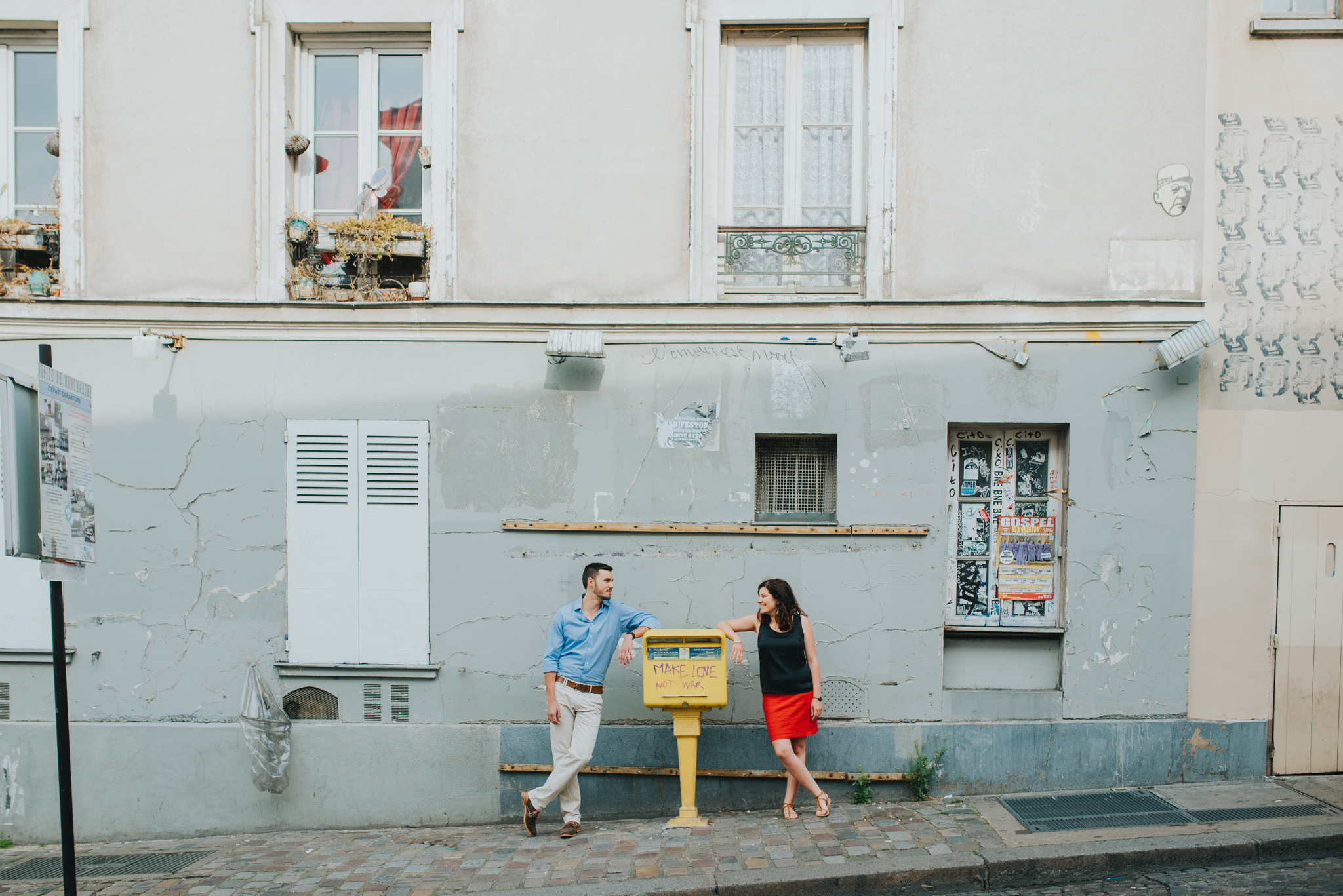 Paris engagement photography couple in love standing next to make love not war sign