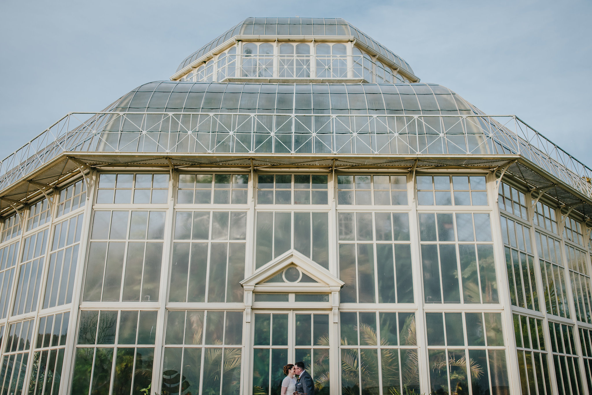 Alternative wedding photography of bride and groom in front of greenhouse at Botanic Gardens Dublin