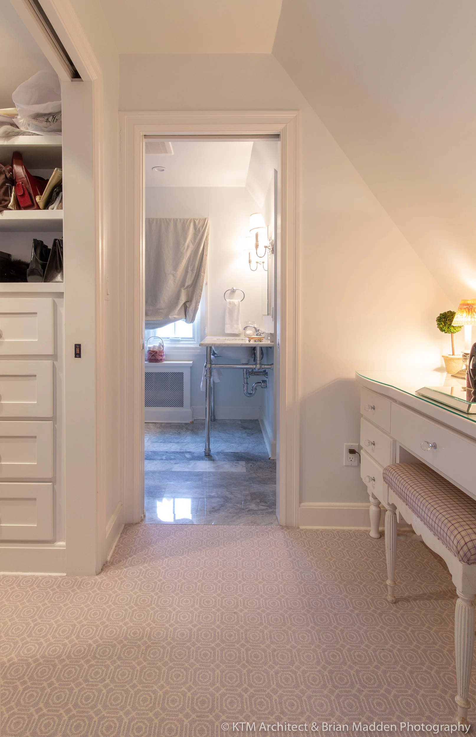 To the right there is a desk where one can put on make-up and jewelry and to the left is a walk-in closet. The bathroom is seen center.