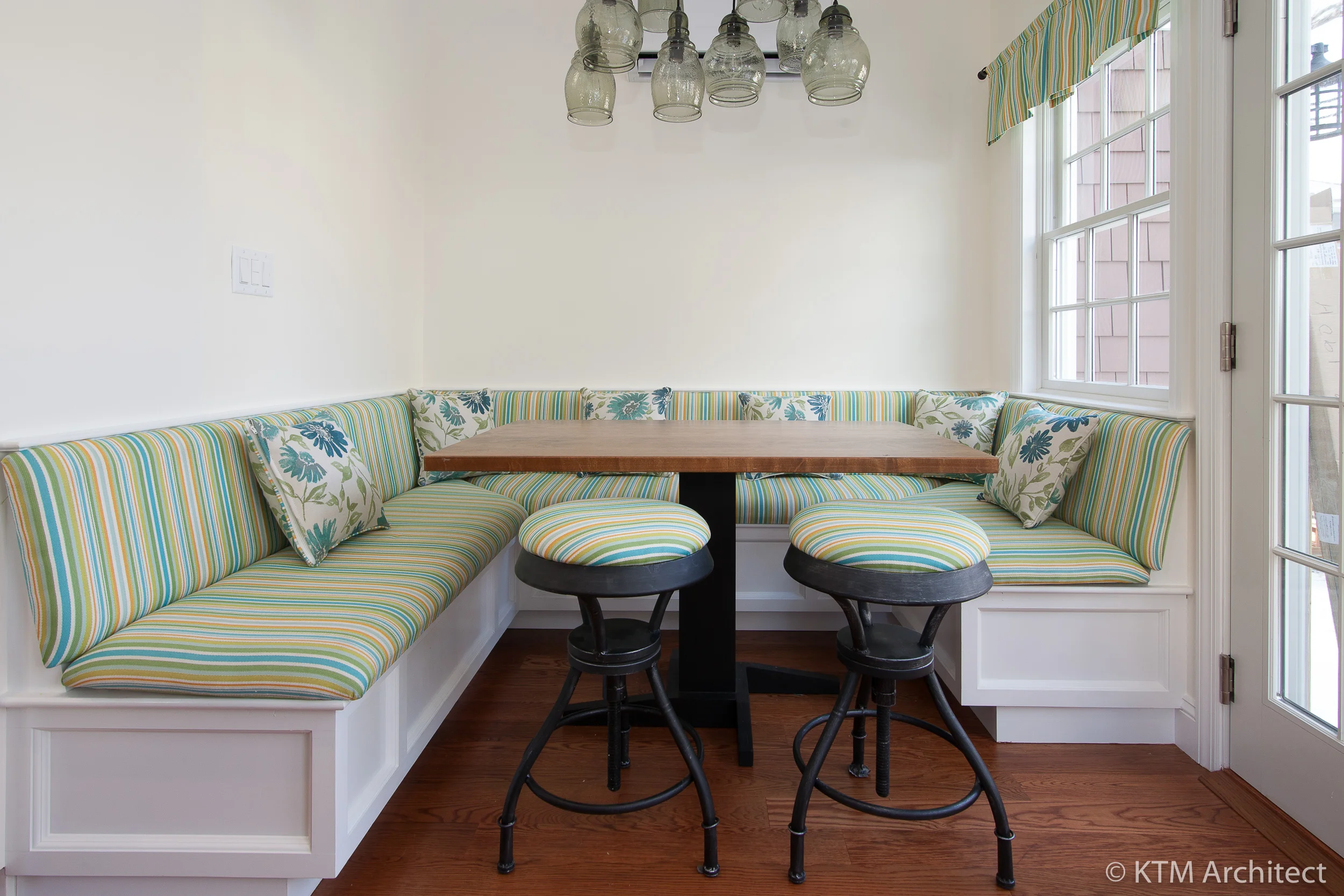The banquette base is done in a white shaker style consistent with the rest of the kitchen, while striped seating adds a punch of color: a great family space for dining, playing cards, or just having a simple chat.