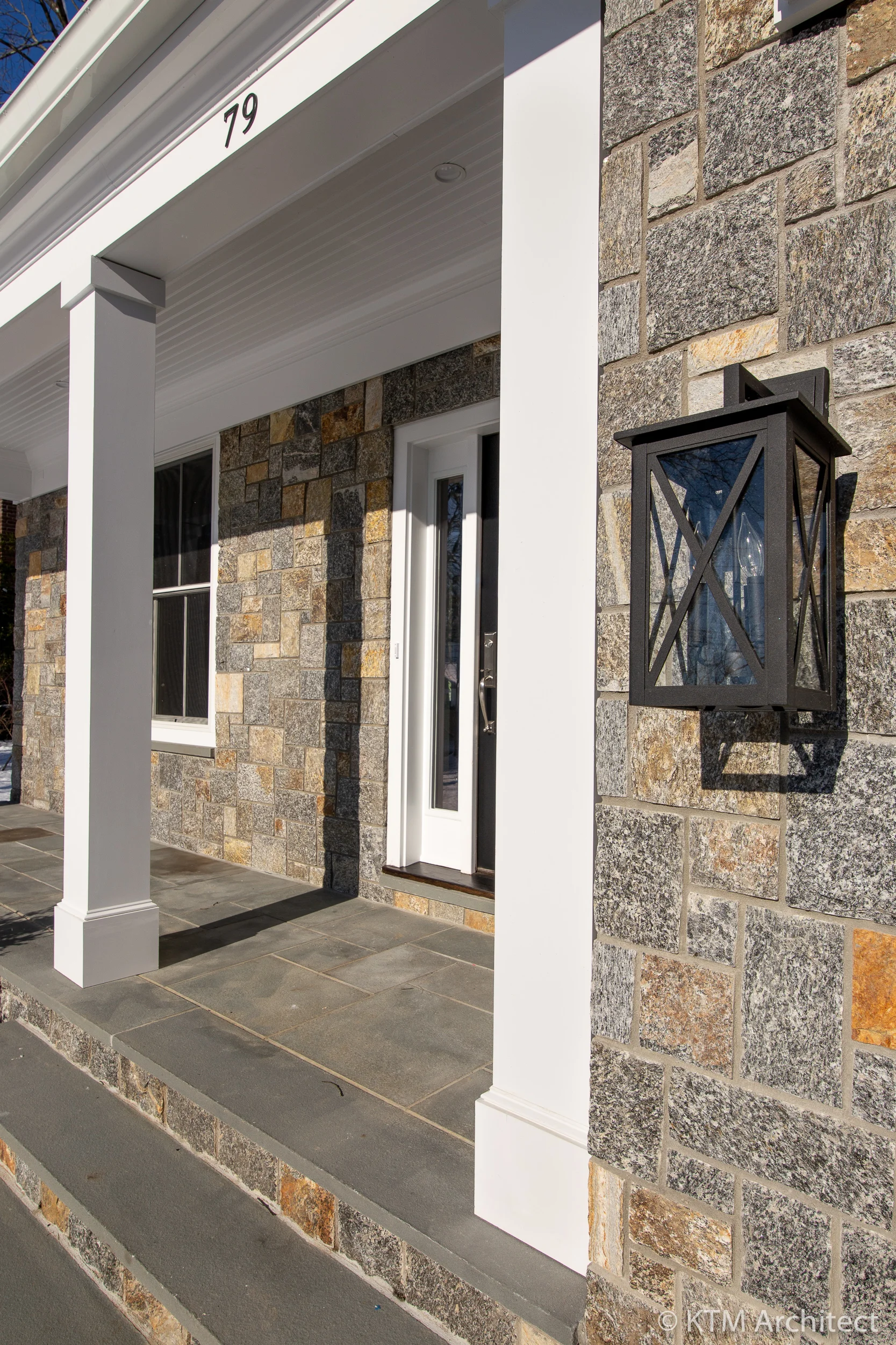 A blue flagstone porch welcomes guests. The exterior lighting is consistent with the transitional feel of the home: referencing the traditional but with a modern touch.