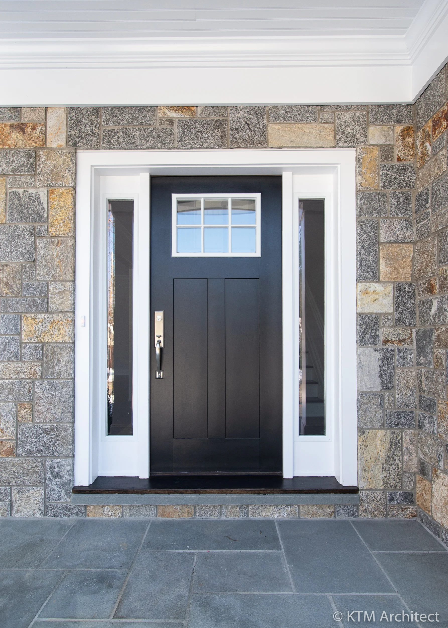 The front entry has a black craftsman style door flanked by sidelights that allow light to stream into the entry.