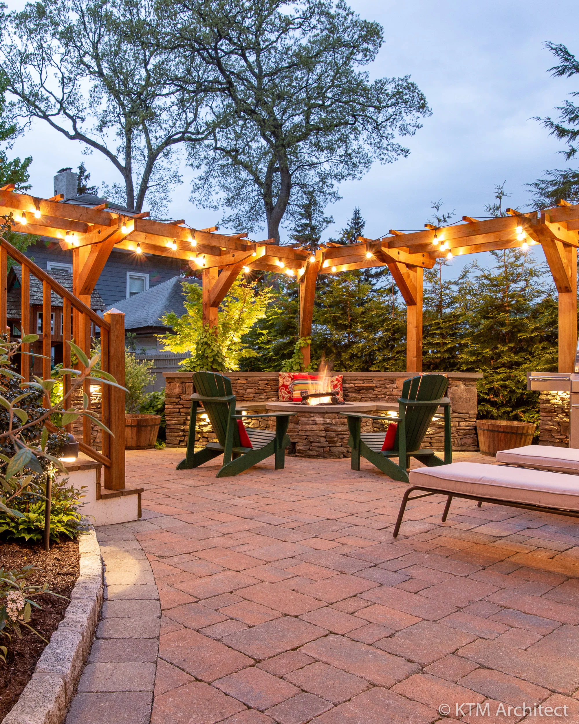 Passing between the garage and home we enter the second courtyard, a lavish entertaining area anchored by stone fire-pit with built-in seating and a surrounding arbor that provides both visual interest and definition to the space. In the evening glow, the radiance and warmth of the area are evident.