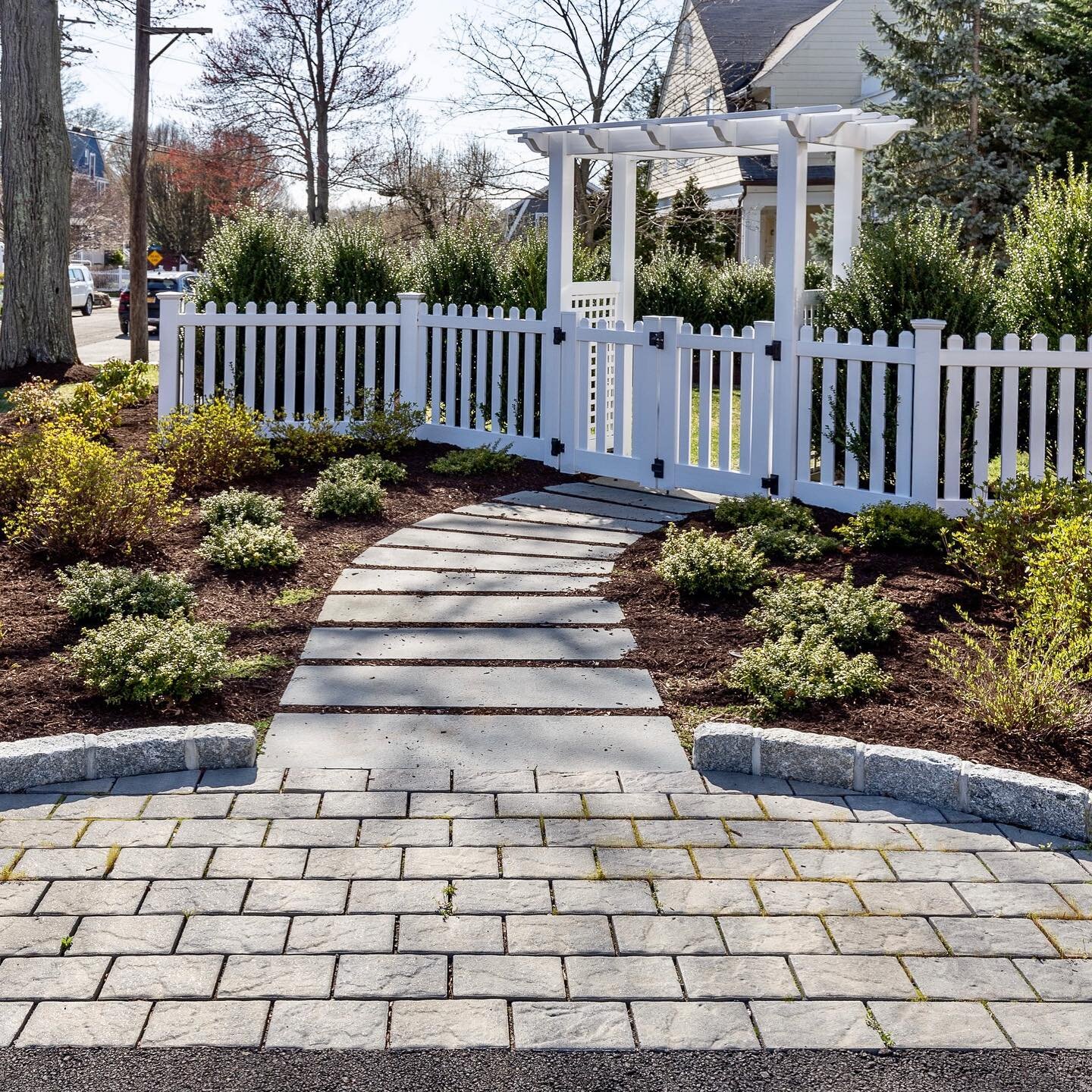 We love this transition from the driveway to the arbor entrance of the yard. Custom cut bluestone makes for a fun and elegant pathway! #path #walkway #landscapedesign #arbor #spring2021 #larchmont #larchmontny #homedesign #home #landscapingideas