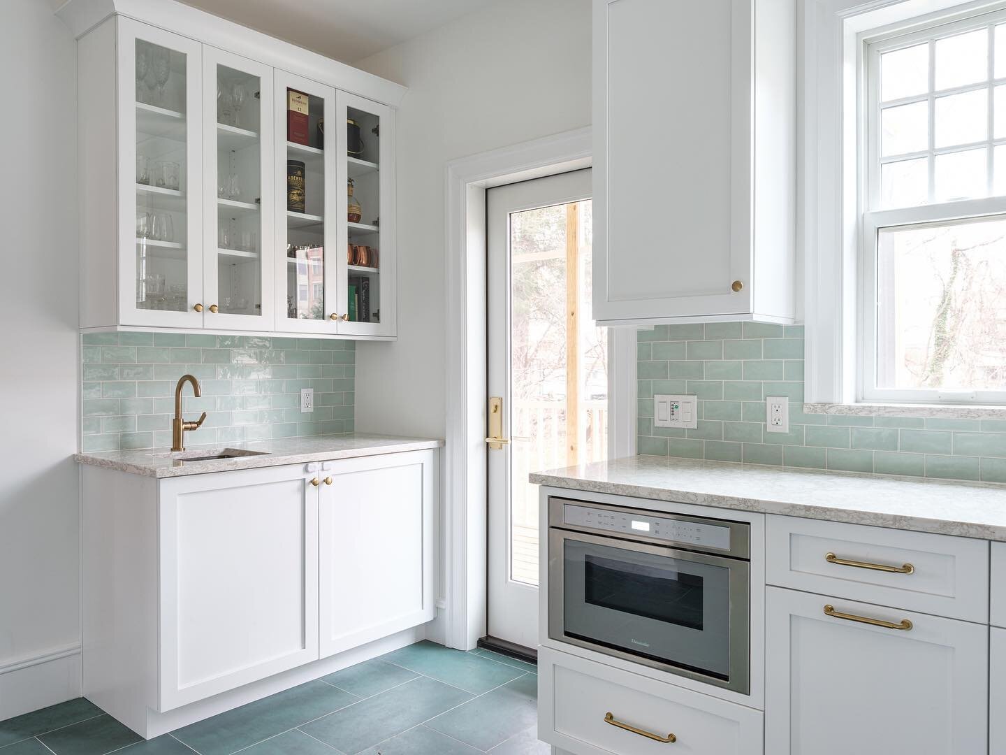 We placed this bar area with its own prep sink along a small wall in this beautiful modern farmhouse kitchen. The crisp white shaker cabinets from @majestic_kitchens_and_baths contrast with the soft green hues of the backsplash and floor. This space 