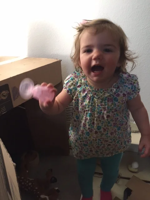 TLC student Daphne has fun with a combination of toys and cardboard boxes at home.