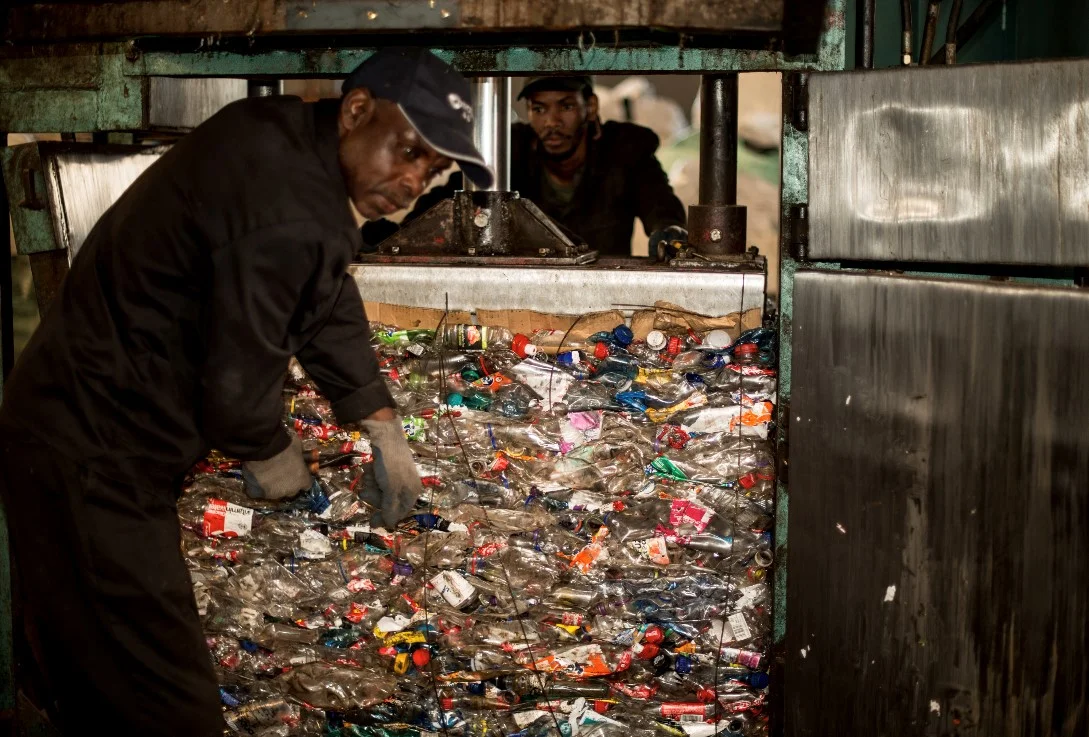 Phillip Julius (front) and another Cannibal Recycling employee prepare to process post-consumer PET plastic bottles. Image © PETCO