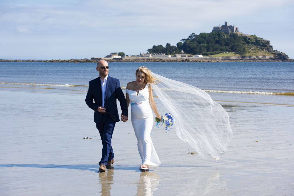 bride and groom walk on the beach at Marazion.jpg