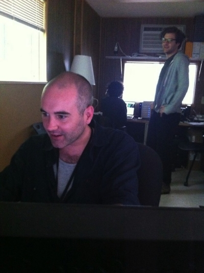 Andrew looks on as Jim problem-solves at his work station.