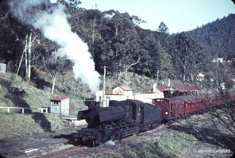A J class steam engine at Warburton station in 1964, a year before the railway line closed. The scene was largely unchanged from 30 years earlier. Photo © Weston Langford .