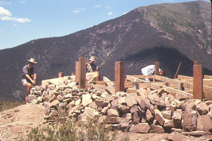 More progress – bearers, joists all strapped together. The track around the face of Feathertop can be seen above the right hand post – midway between the top of the post and the summit. The track was a natural cattle pad when cattle were permitted to graze up in the high country.