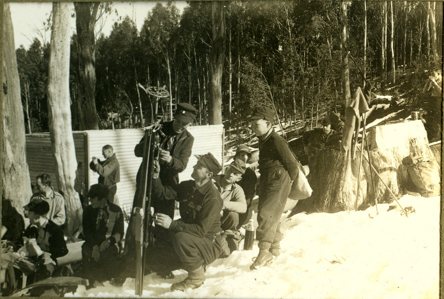 Eric Douglas and family taking a break July 1935. The photo gives an idea of ski fashions of the time. The structure in the background is yet to be identified, it may have been a kiosk, a shelter hut, toilets, ski hire or a first aid post. Please send a message if you have any idea.